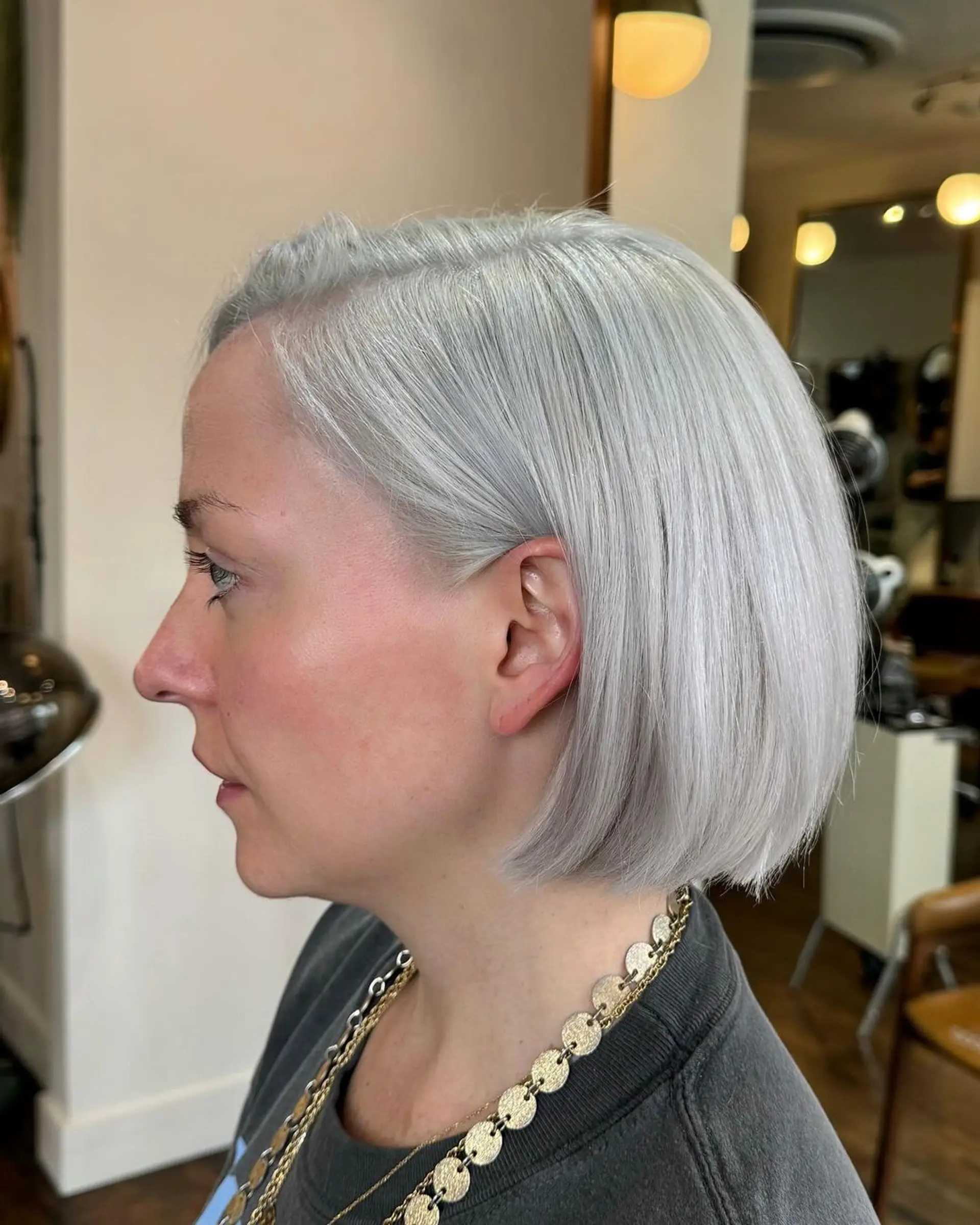 A sleek short bob with silver color and a side part, featuring blunt cut ends for a polished appearance. 1