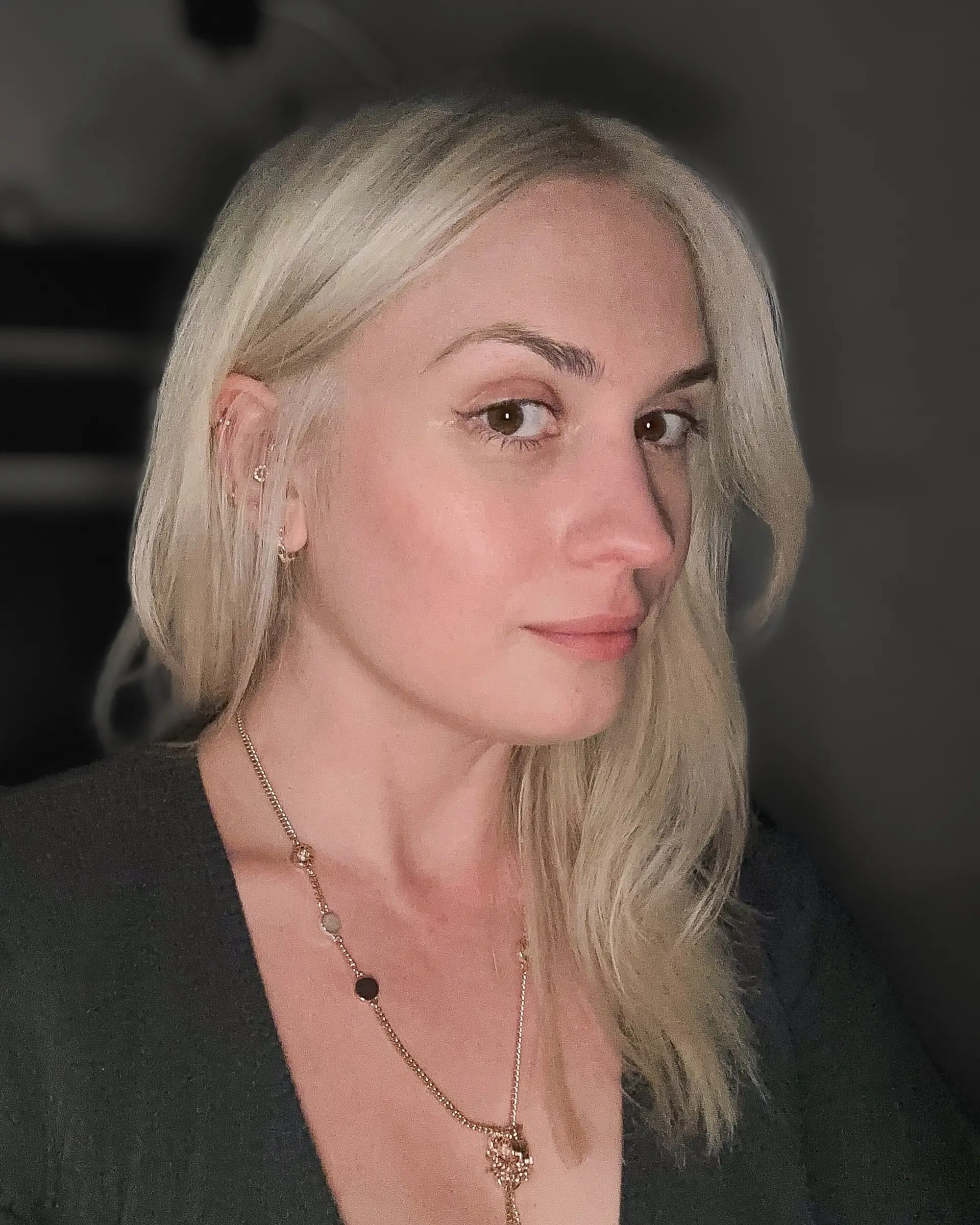 Medium-length platinum blonde hair styled with subtle face-framing layers and tucked behind one ear. 1