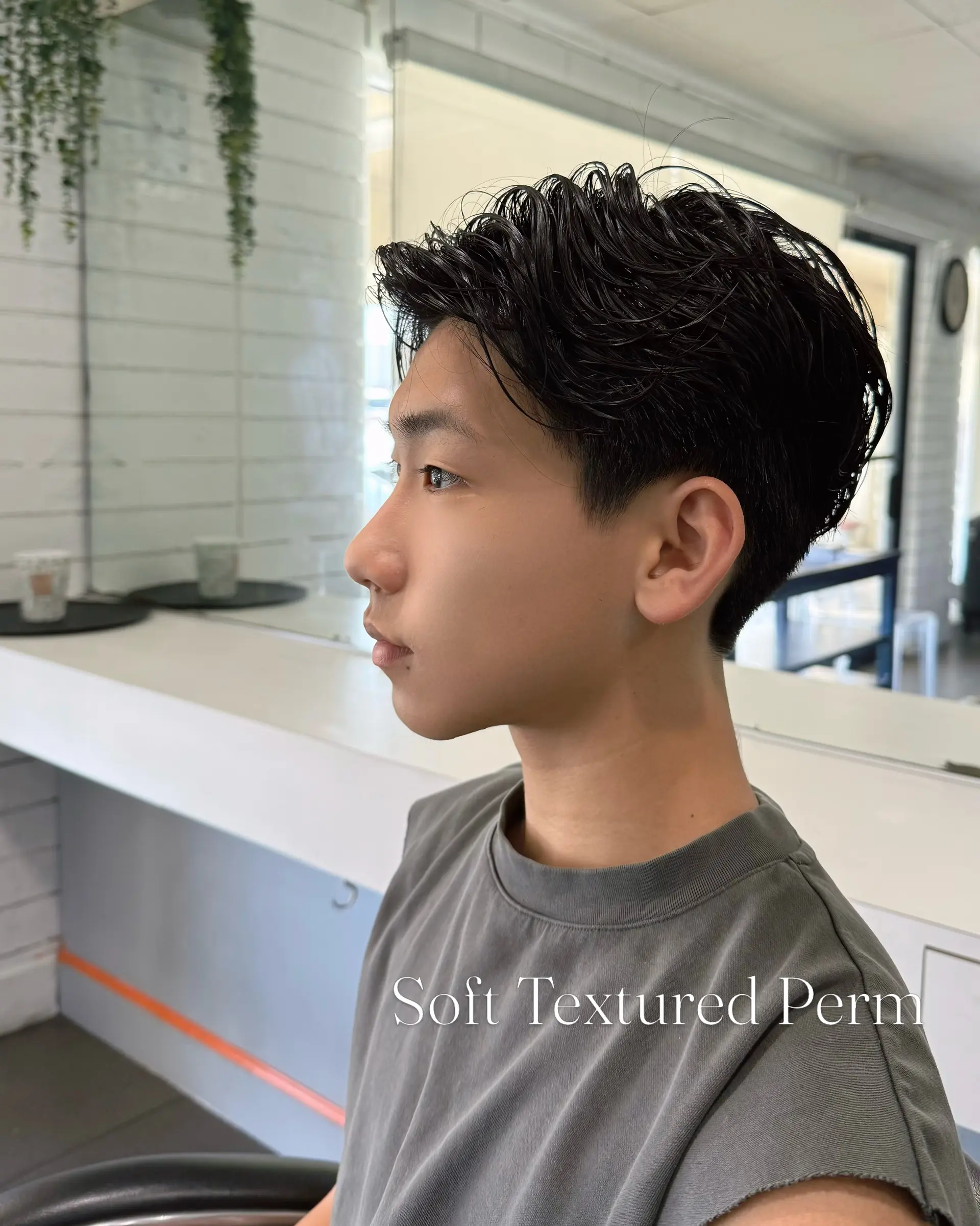 A short men's cut enhanced with a soft textured perm that creates effortless movement, natural waves, and light volume. 1
