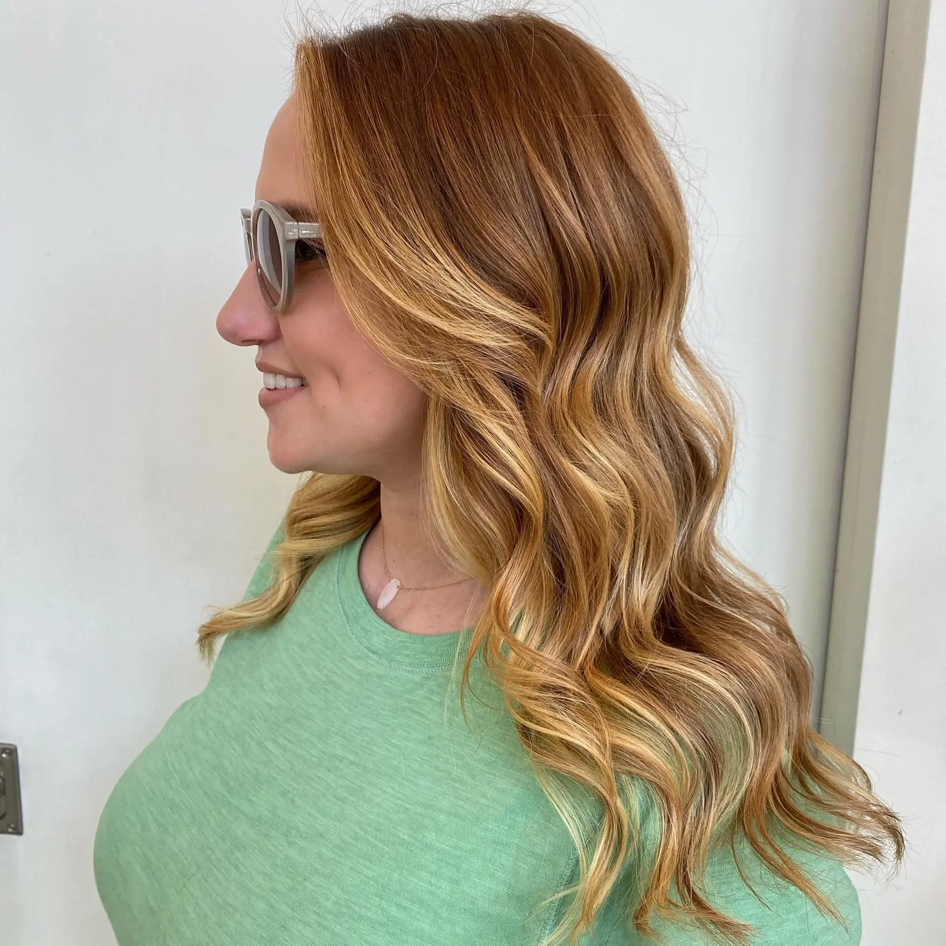 Dimensional strawberry blonde and warm golden balayage styled into soft, flowing waves. 1