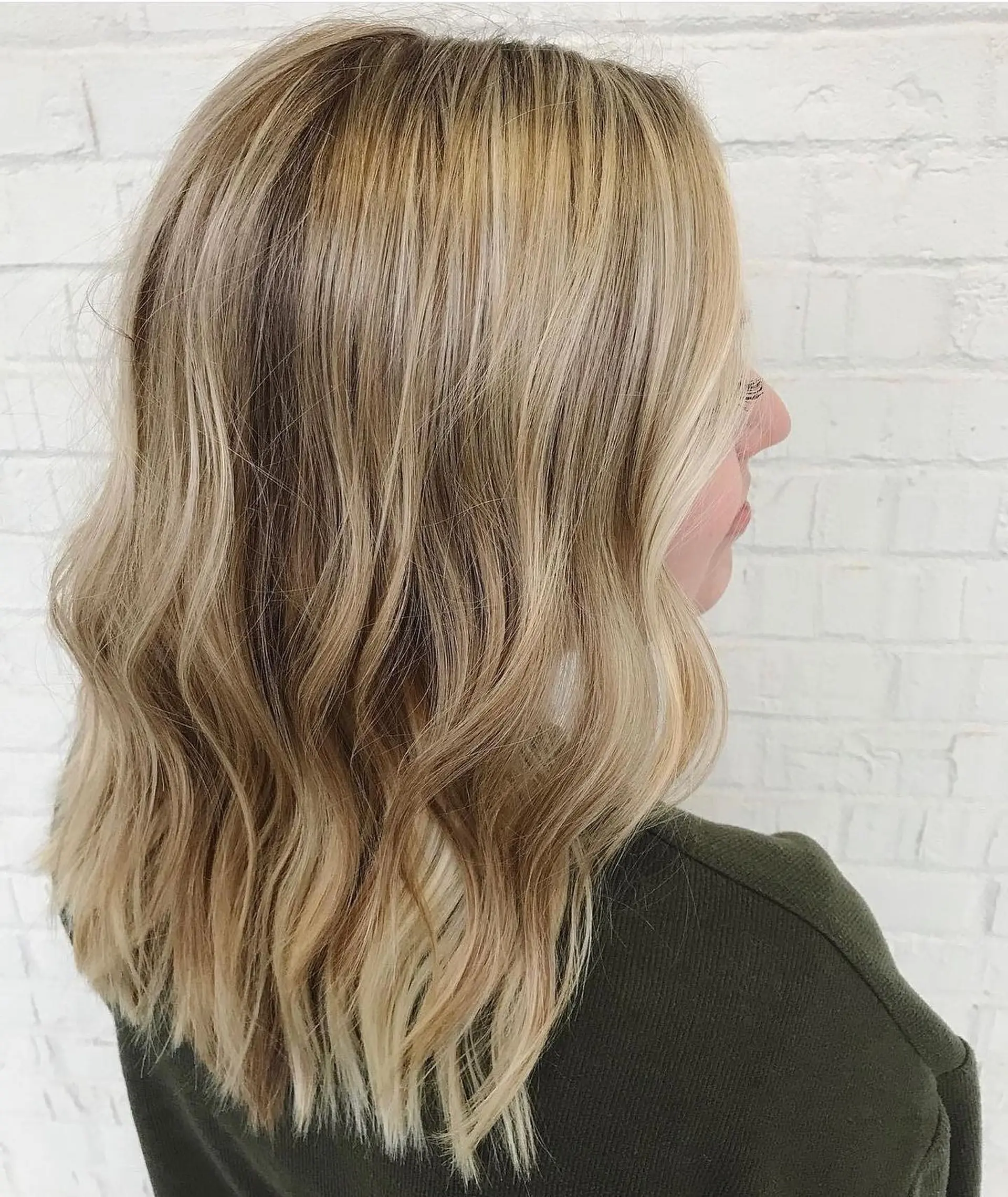 Shoulder-length dimensional blonde hair cut with light texture and styled in soft, loose waves. 1