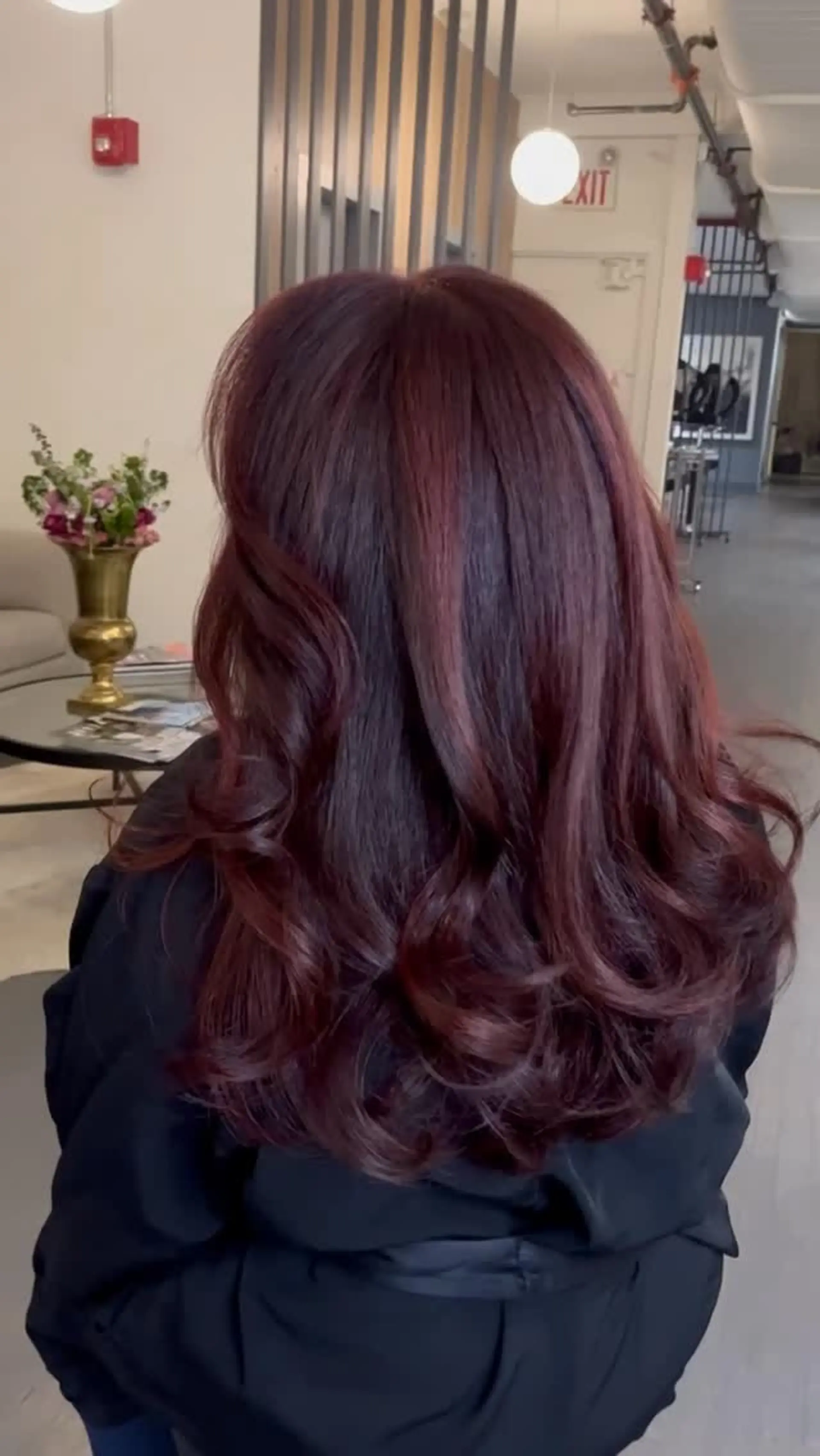 Long layered dark hair enhanced with rich red and burgundy balayage highlights, styled with soft curls toward the ends. 1