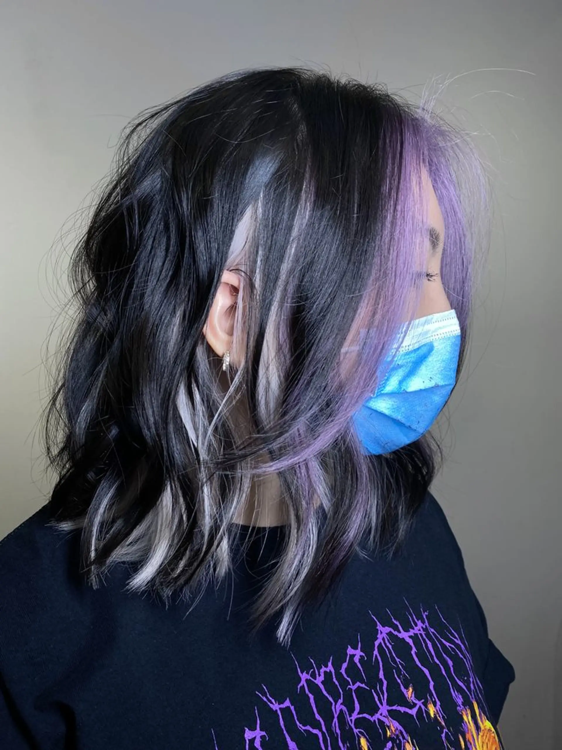 Medium-length wavy hairstyle with a black base, blending into lilac and silver tones. Features include face-framing highlights and layered choppy ends. 1