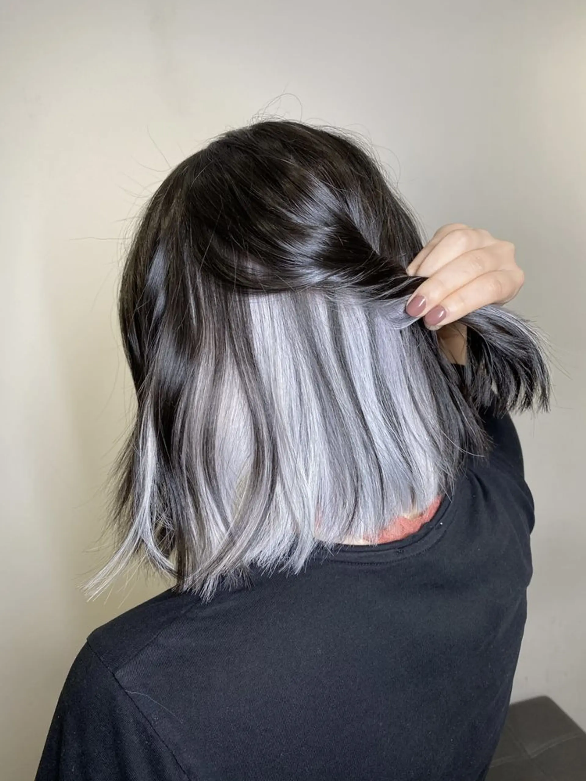 Medium-length wavy hairstyle with a black base, blending into lilac and silver tones. Features include face-framing highlights and layered choppy ends. 2