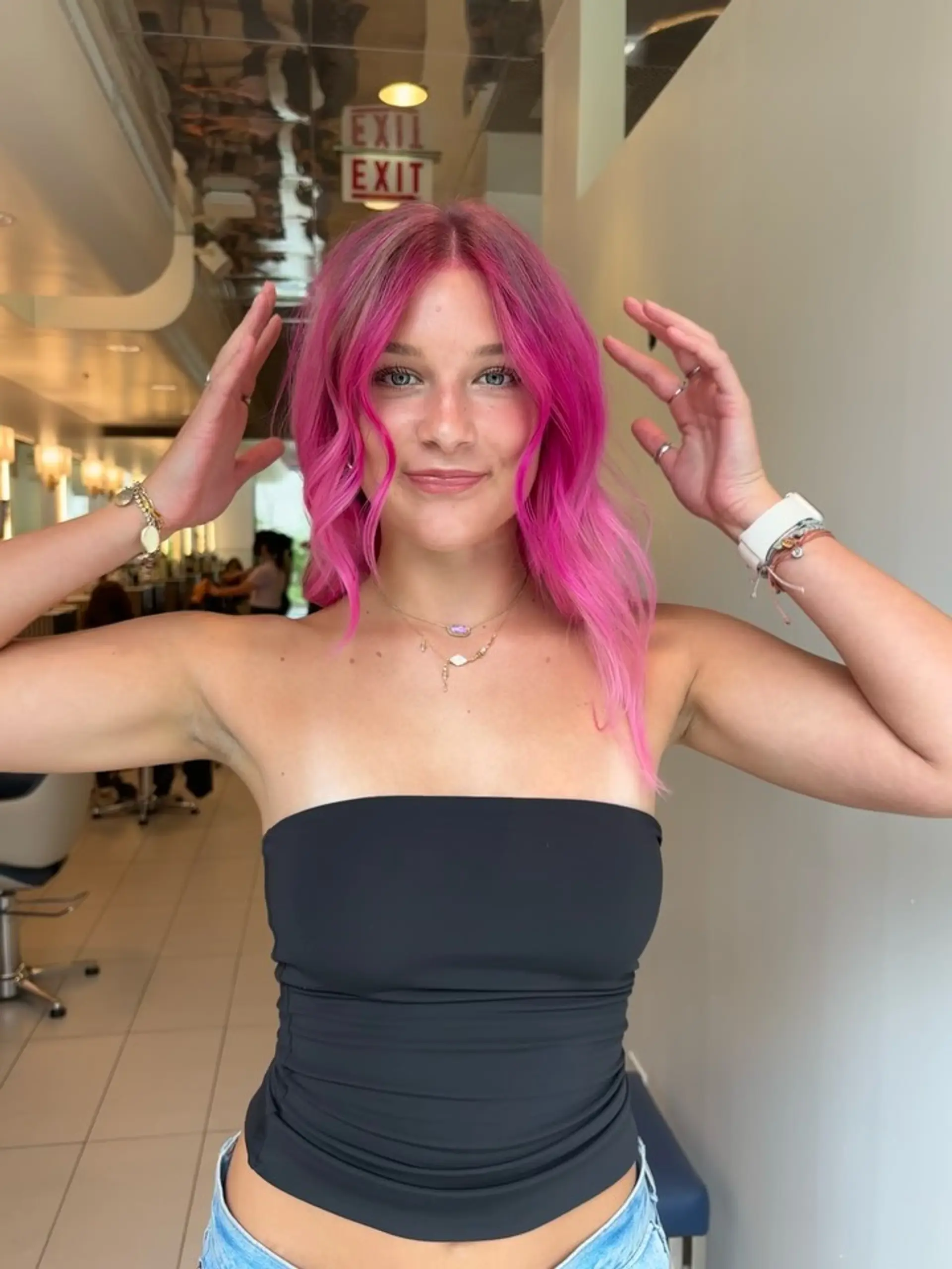 Medium-length bright hot pink hair styled with loose textured waves, face-framing layers, and a center part. 1