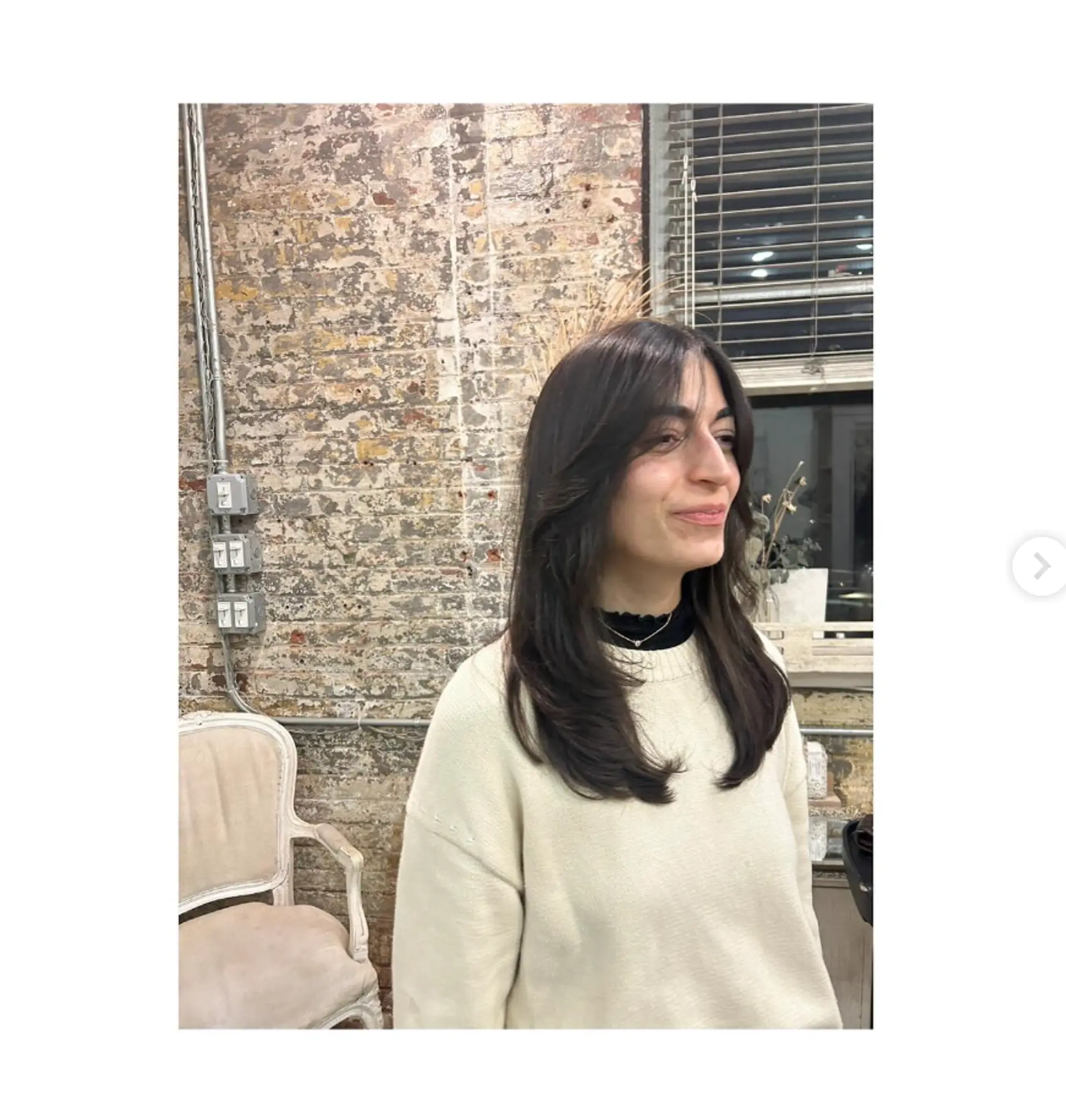 A medium length haircut with face-framing layers and curtain bangs. 1