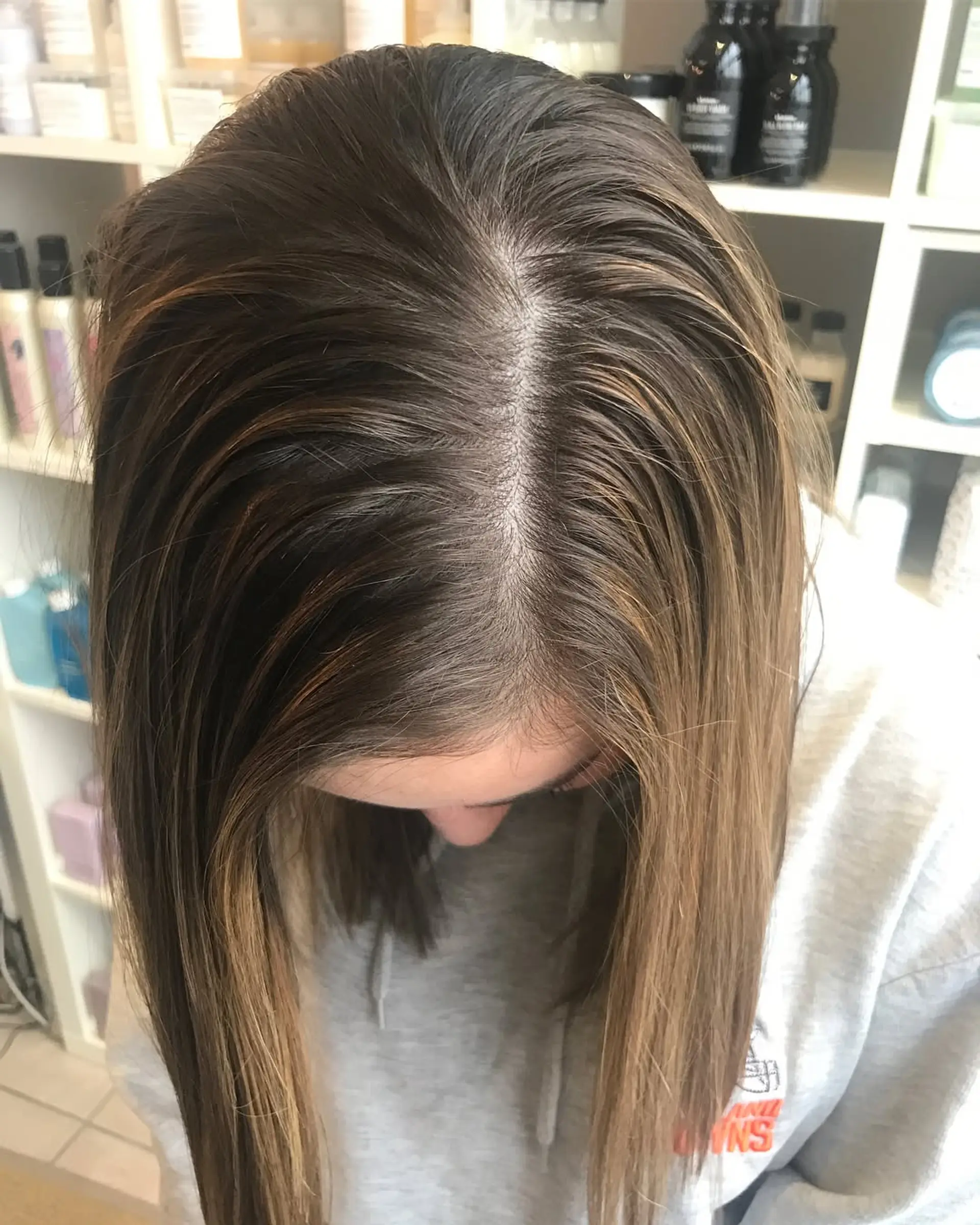 Straight medium-length brunette hair showcasing a seamless lived-in caramel balayage with a blended shadow root. 1