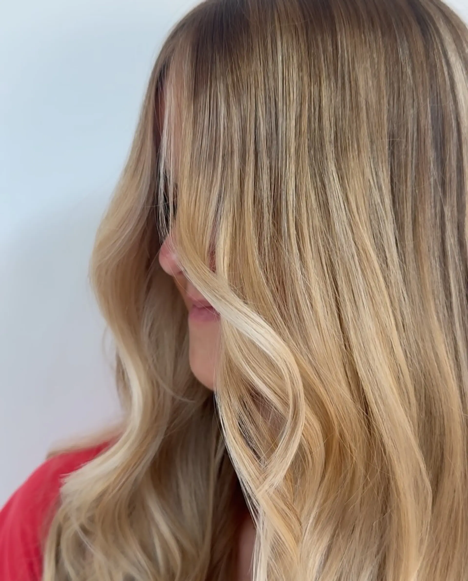 Dimensional honey blonde balayage styled with soft, elegant face-framing waves. 1