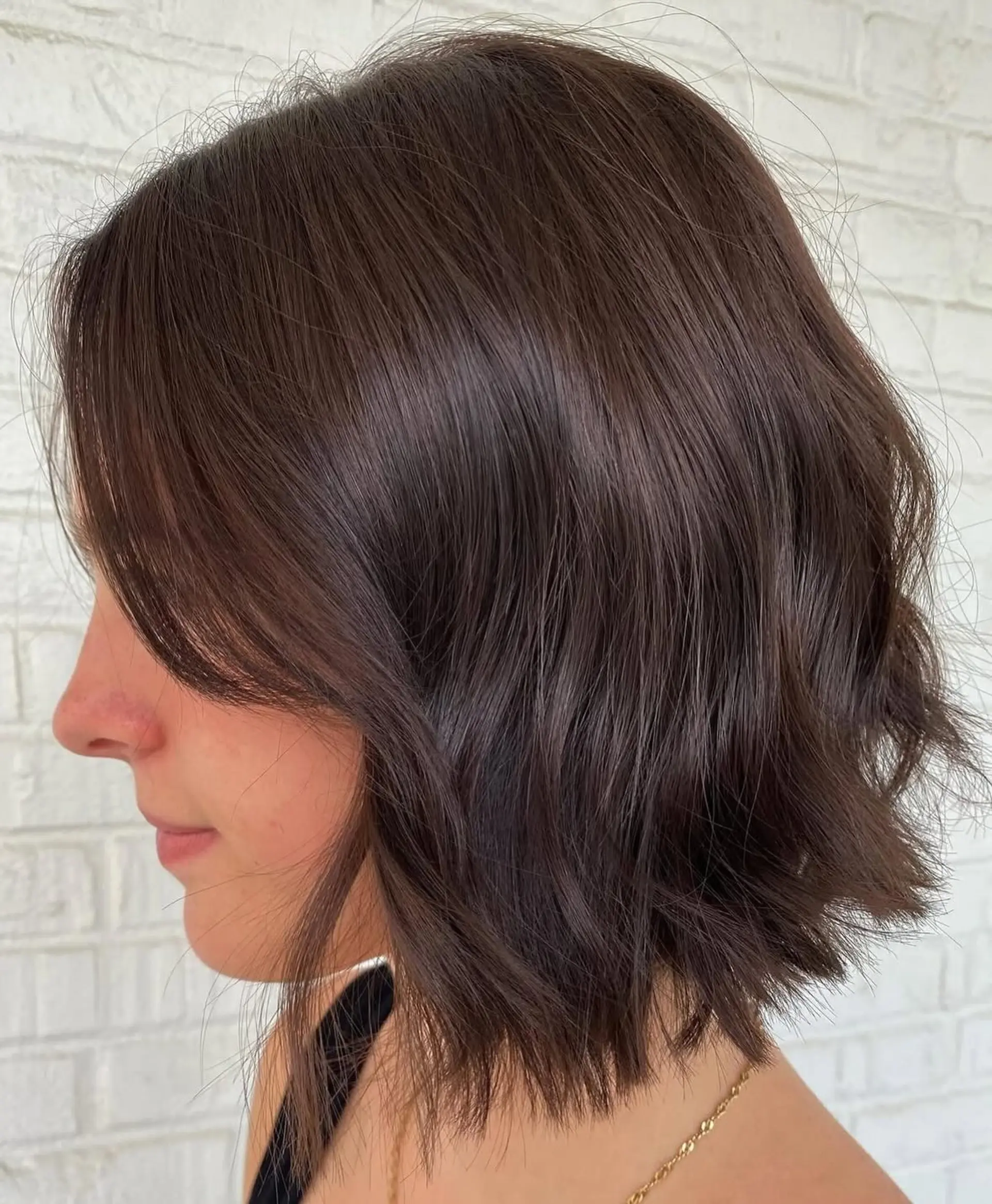 A textured chin-length brunette bob styled with loose, subtle waves and piecey ends. 1