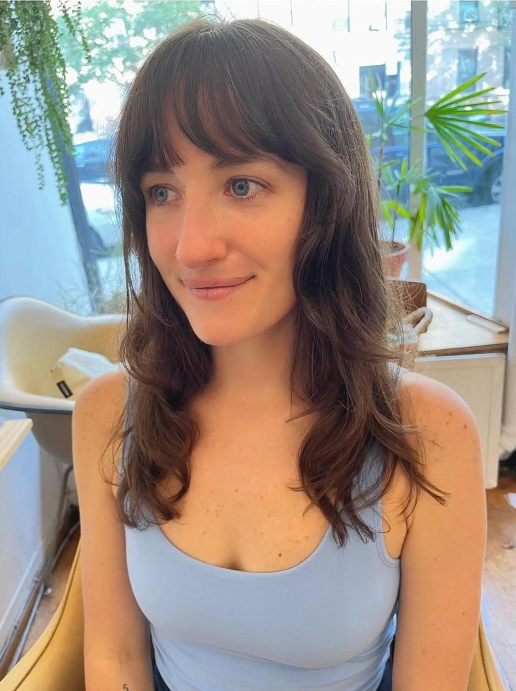 Medium-length brunette waves with long curtain bangs and subtle layers.