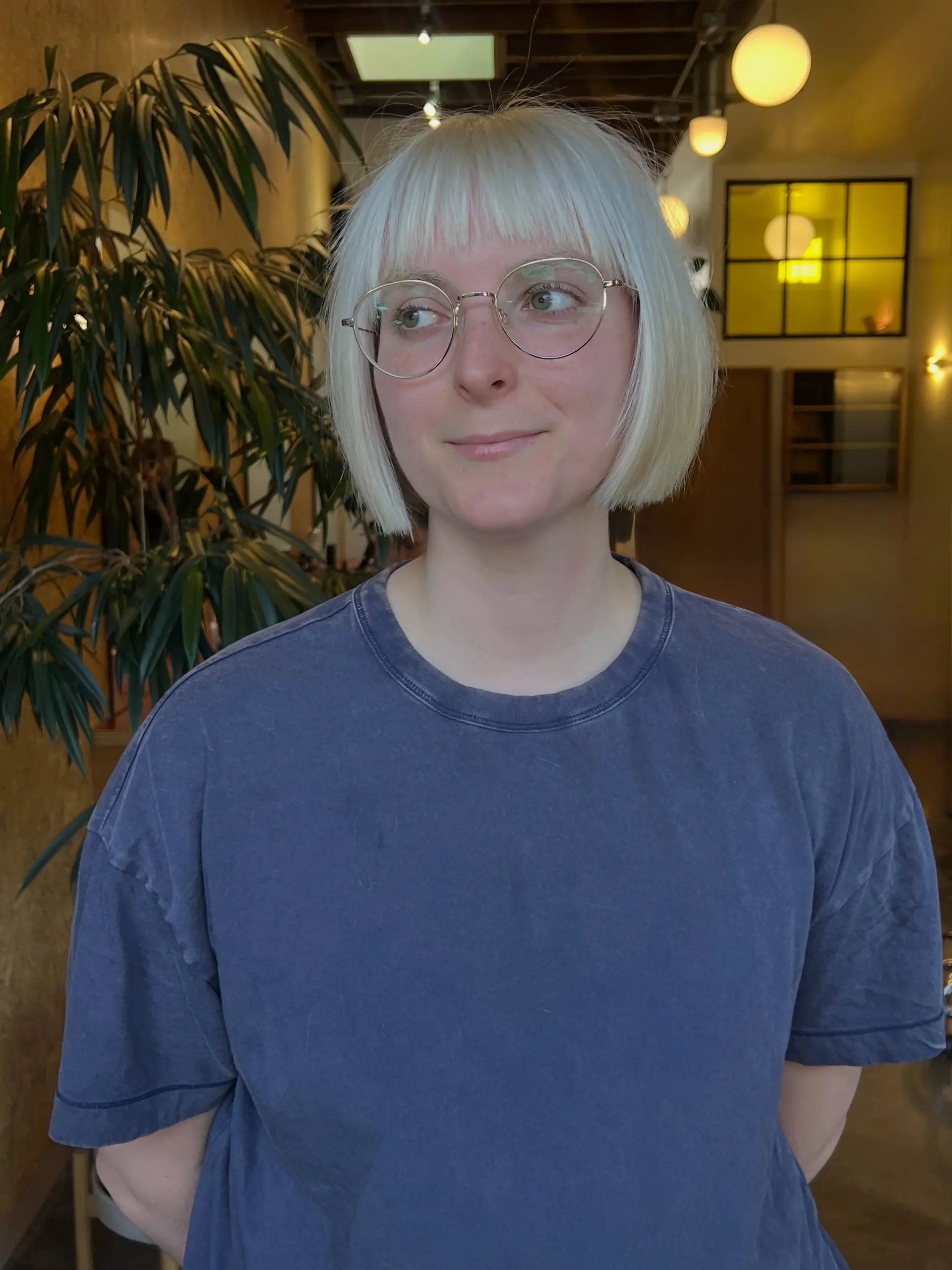 A sharp, straight platinum blonde chin-length bob with full bangs. 1