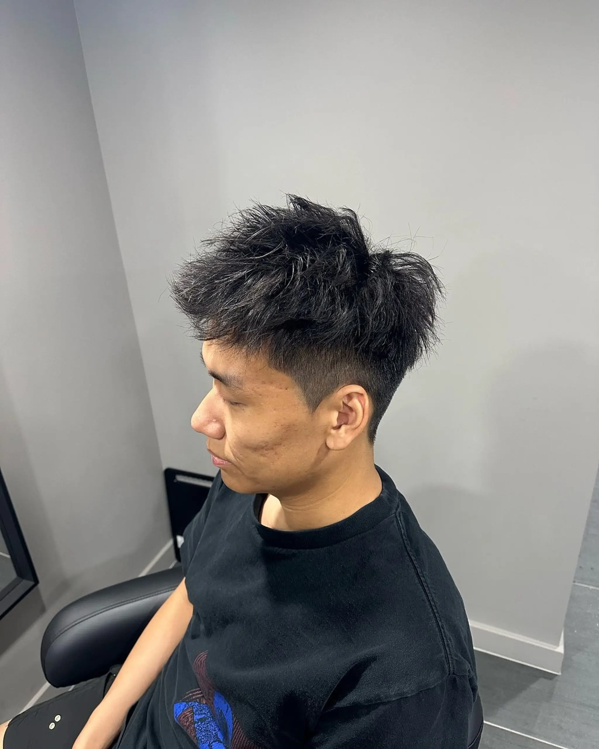 An edgy hairstyle with a high fade on the sides, transitioning into loose, wavy spikes on the top for a textured, modern look.