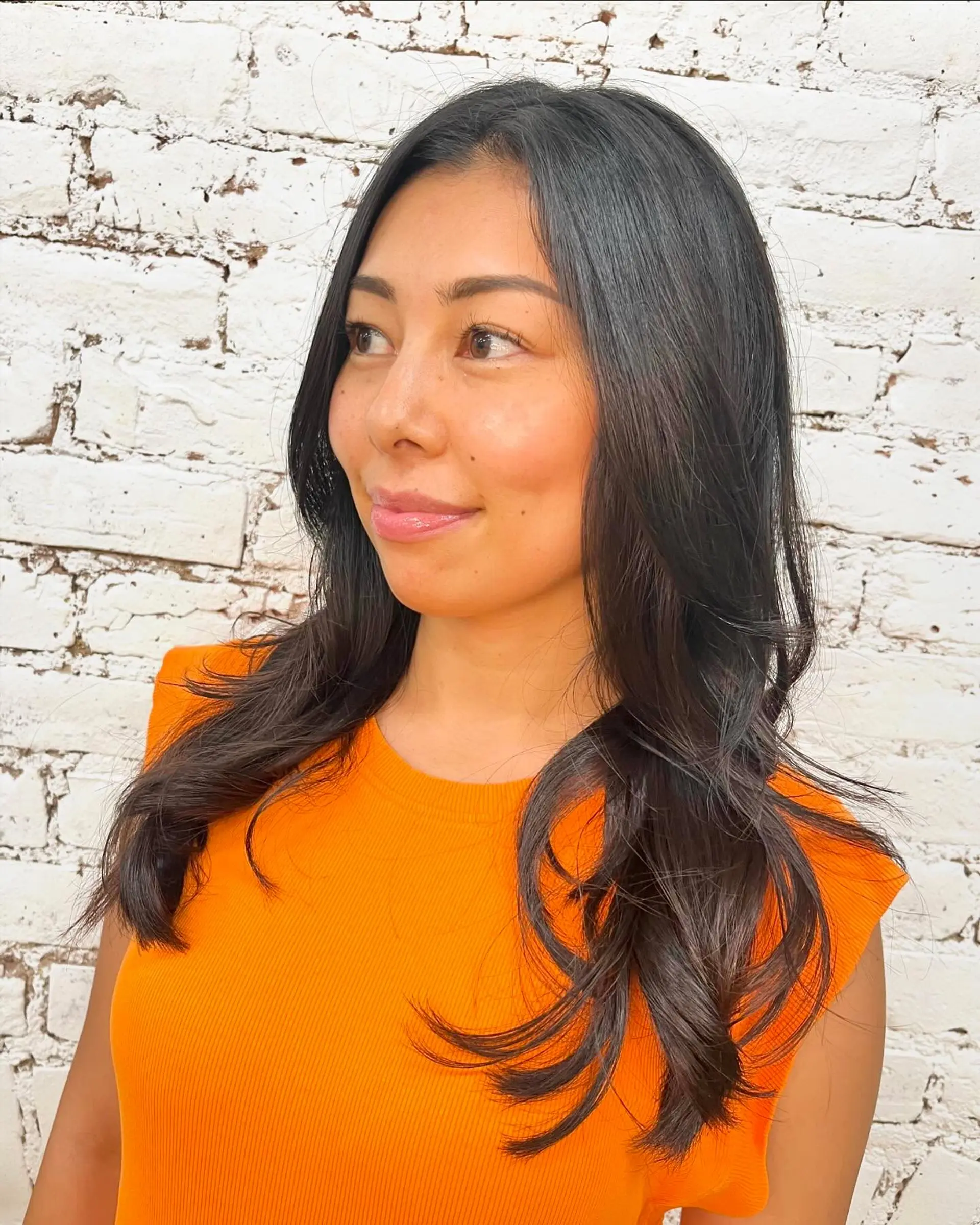 Long dark layered haircut styled with a smooth blowout and soft, curved flipped ends. 1
