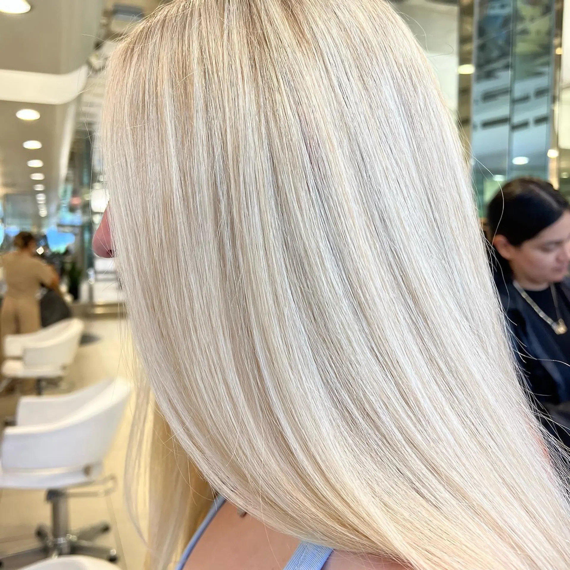 Sleek and glossy long hair colored in a seamless, luminous platinum blonde tone. 1