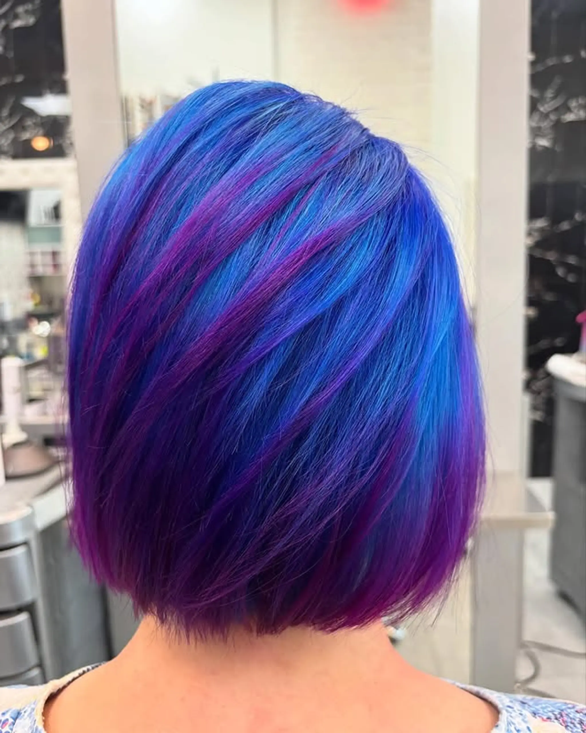 A sleek, straight bob with electric blue and purple highlights.
