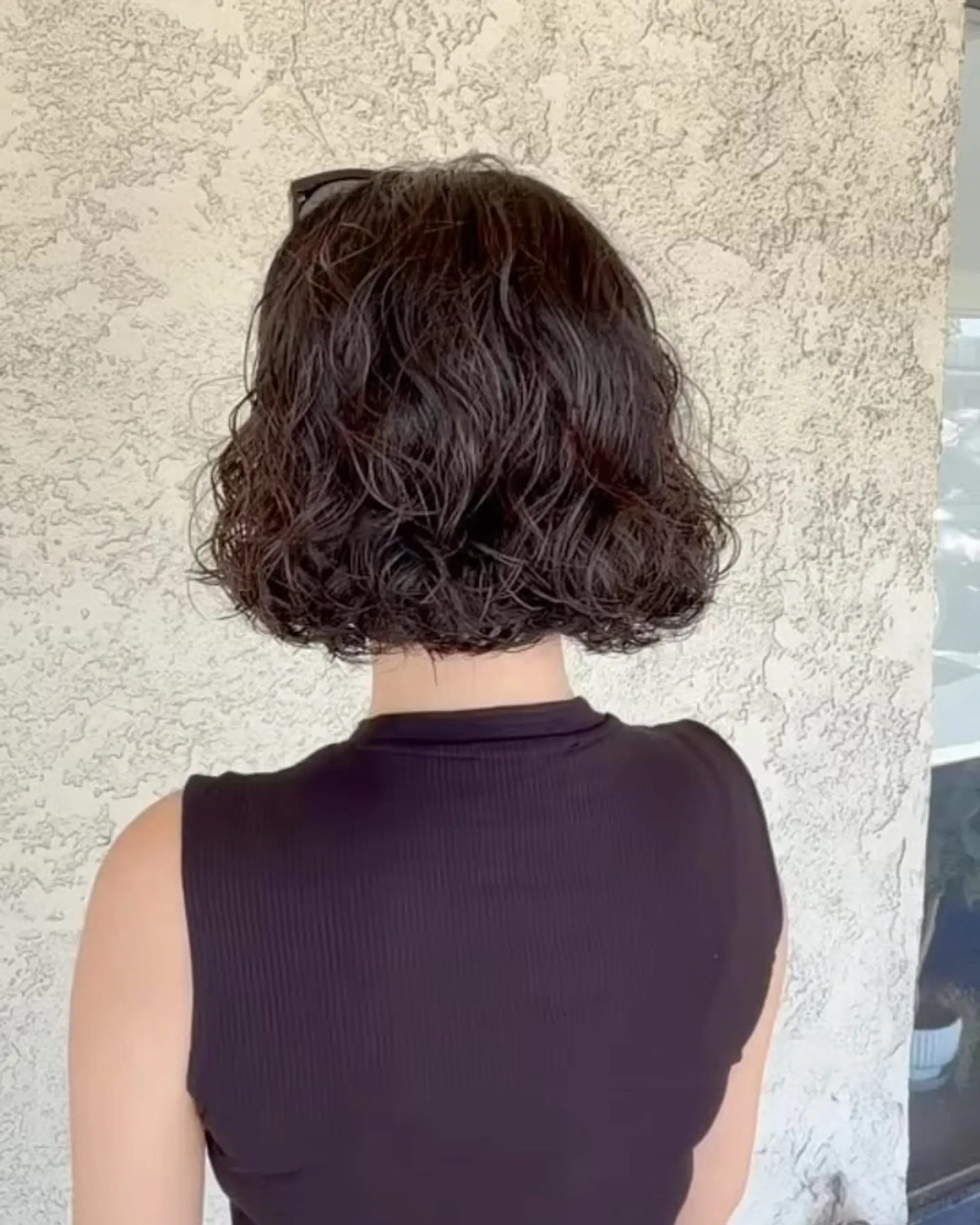 A chin-length bob styled with soft, airy curls and textured bounce. 1