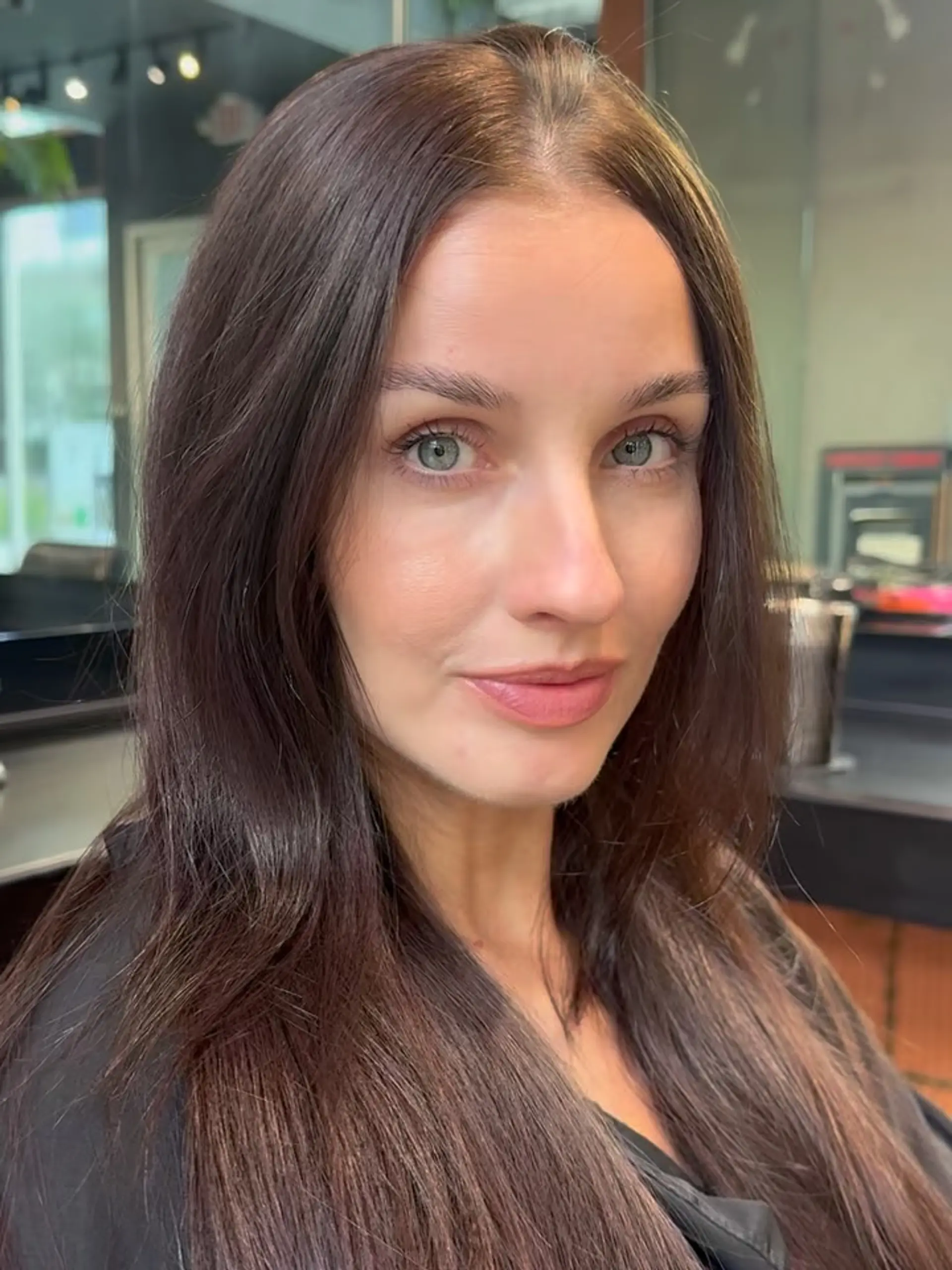 A glossy, deep chocolate brown color styled straight and smooth with a soft center part. 1