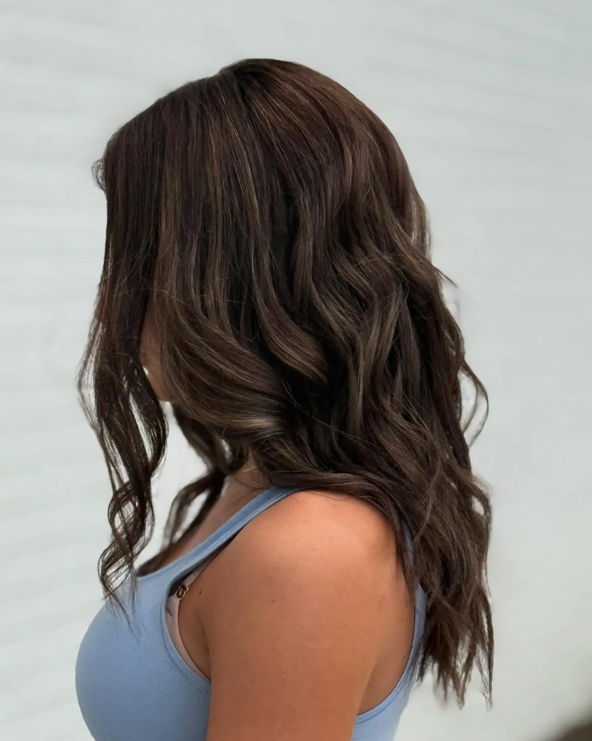 Long dimensional brunette hair styled in soft, cascading waves. 1