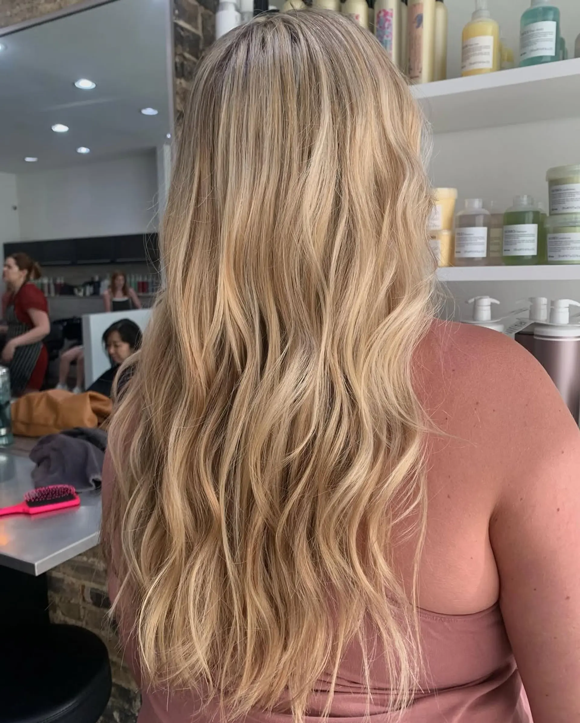 A long, wavy hairstyle featuring a dimensional blonde color with sun-kissed highlights and natural lowlights, creating a voluminous and effortlessly chic beach wave effect. 1