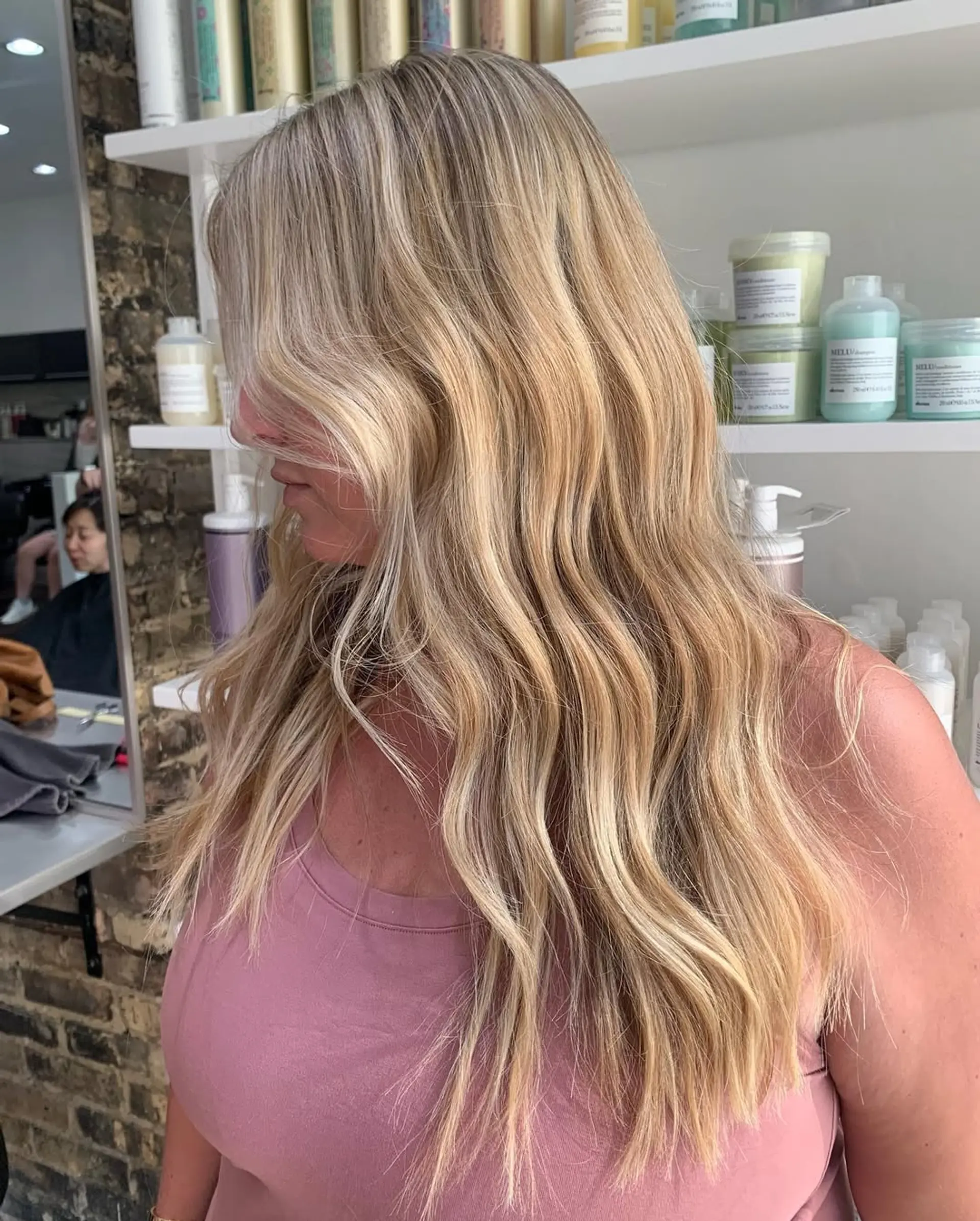A long, wavy hairstyle featuring a dimensional blonde color with sun-kissed highlights and natural lowlights, creating a voluminous and effortlessly chic beach wave effect. 2