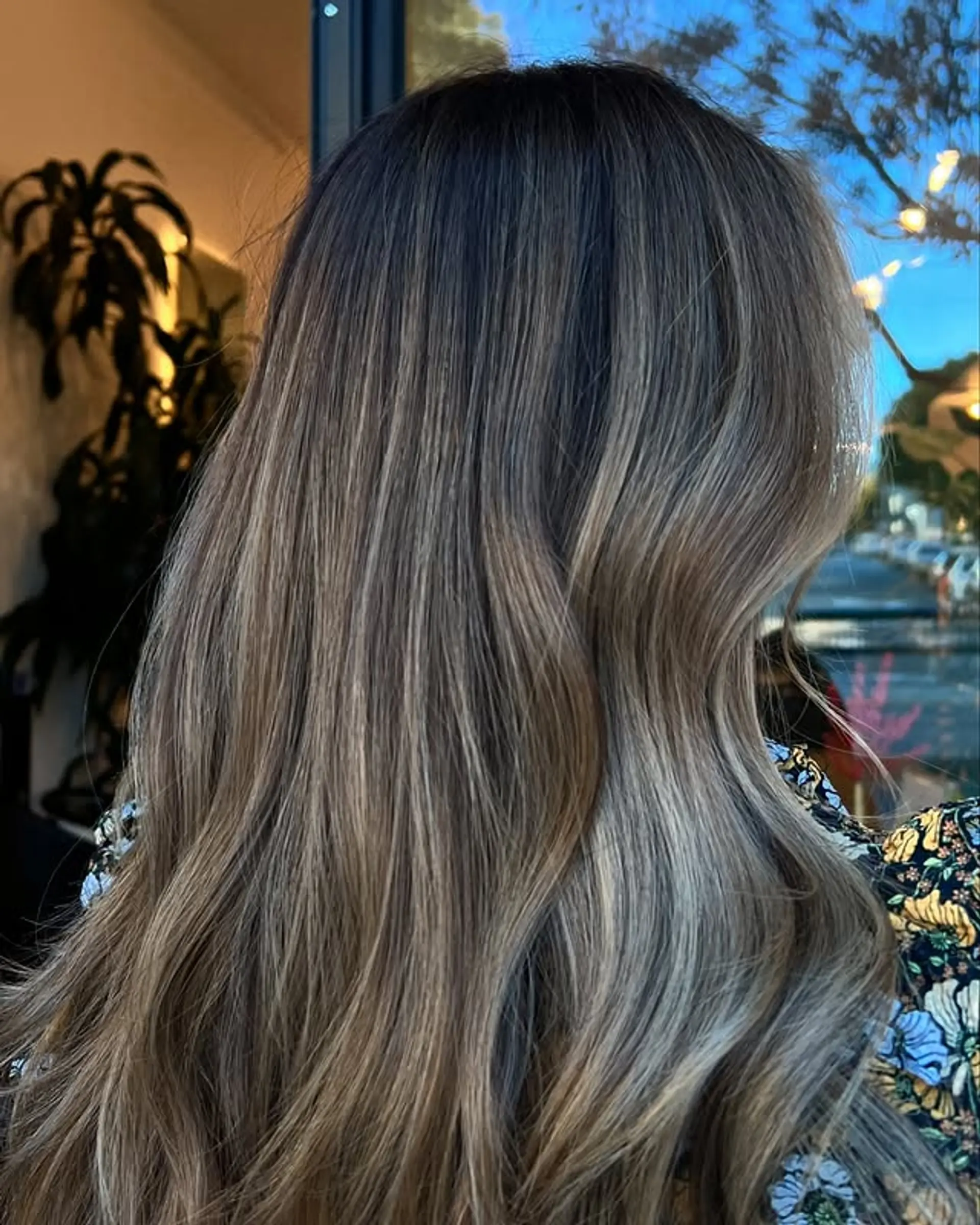 Long, wavy hair with a dark rooted balayage that fades into an ash blonde. 1