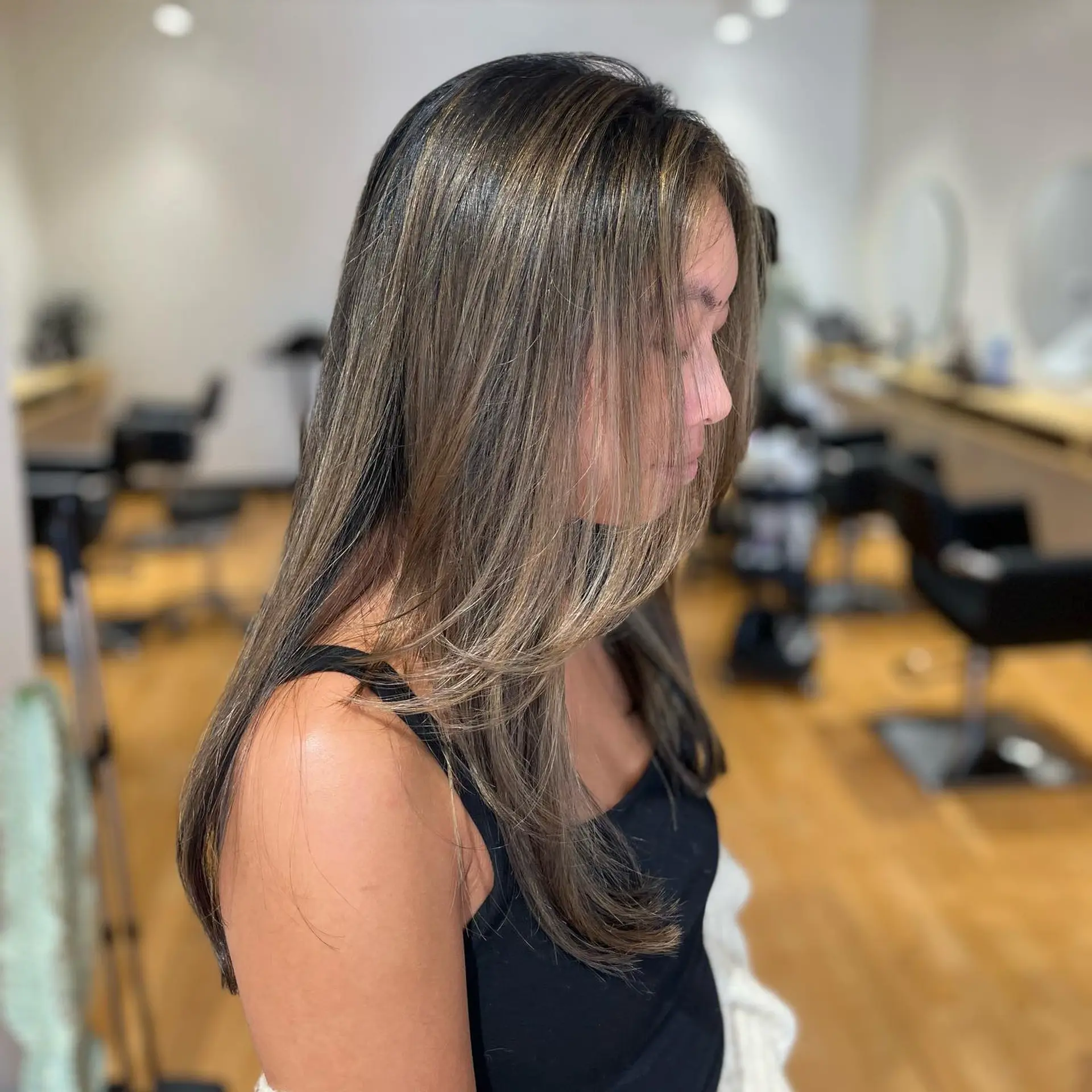 A sleek, long ash brown balayage featuring blended dimensional highlights and soft face-framing layers. 1