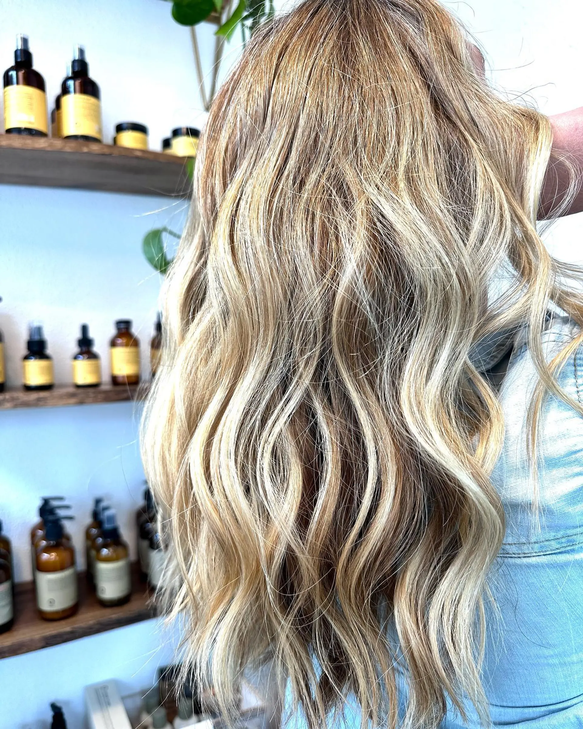 Long dimensional blonde hair featuring smooth balayage highlights styled in loose, textured waves. 1