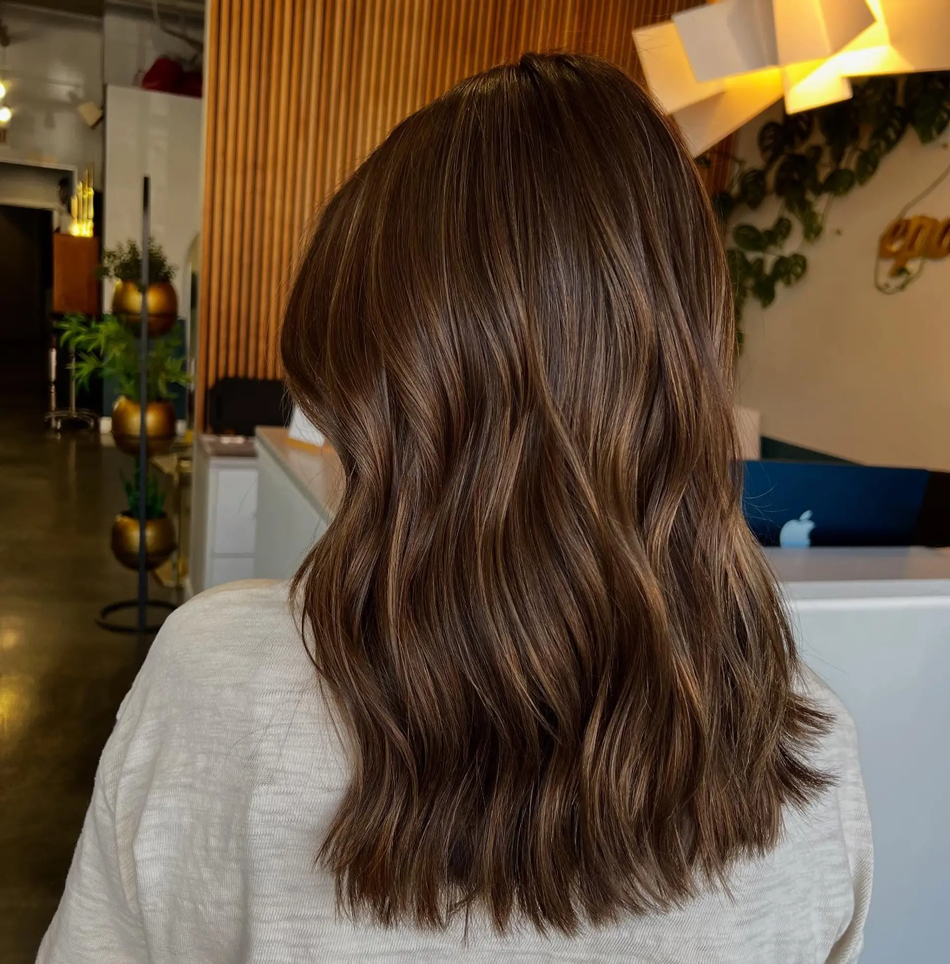 A medium-length wavy hairstyle with subtle bronze highlights. 1