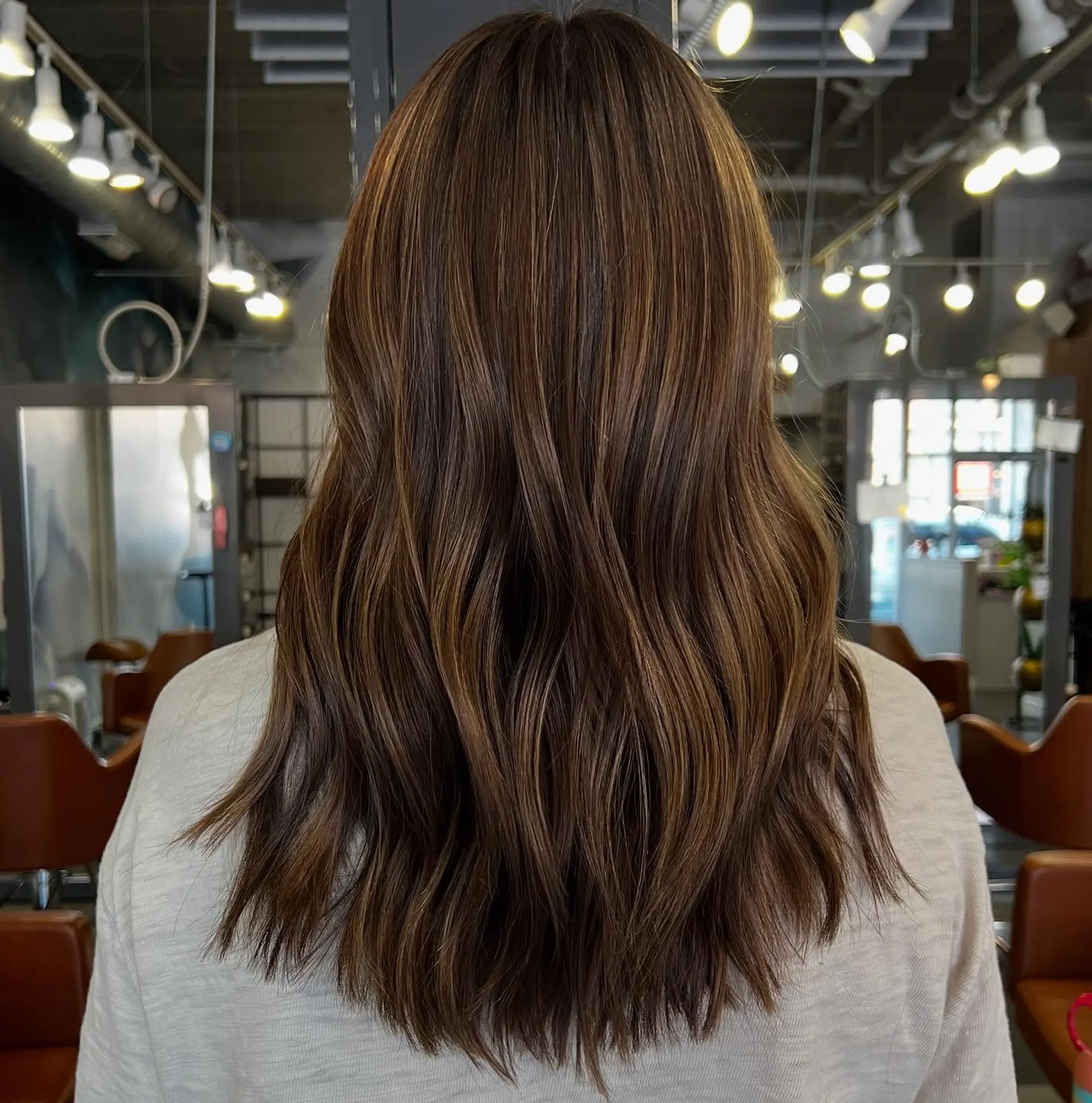 A medium-length wavy hairstyle with subtle bronze highlights. 2