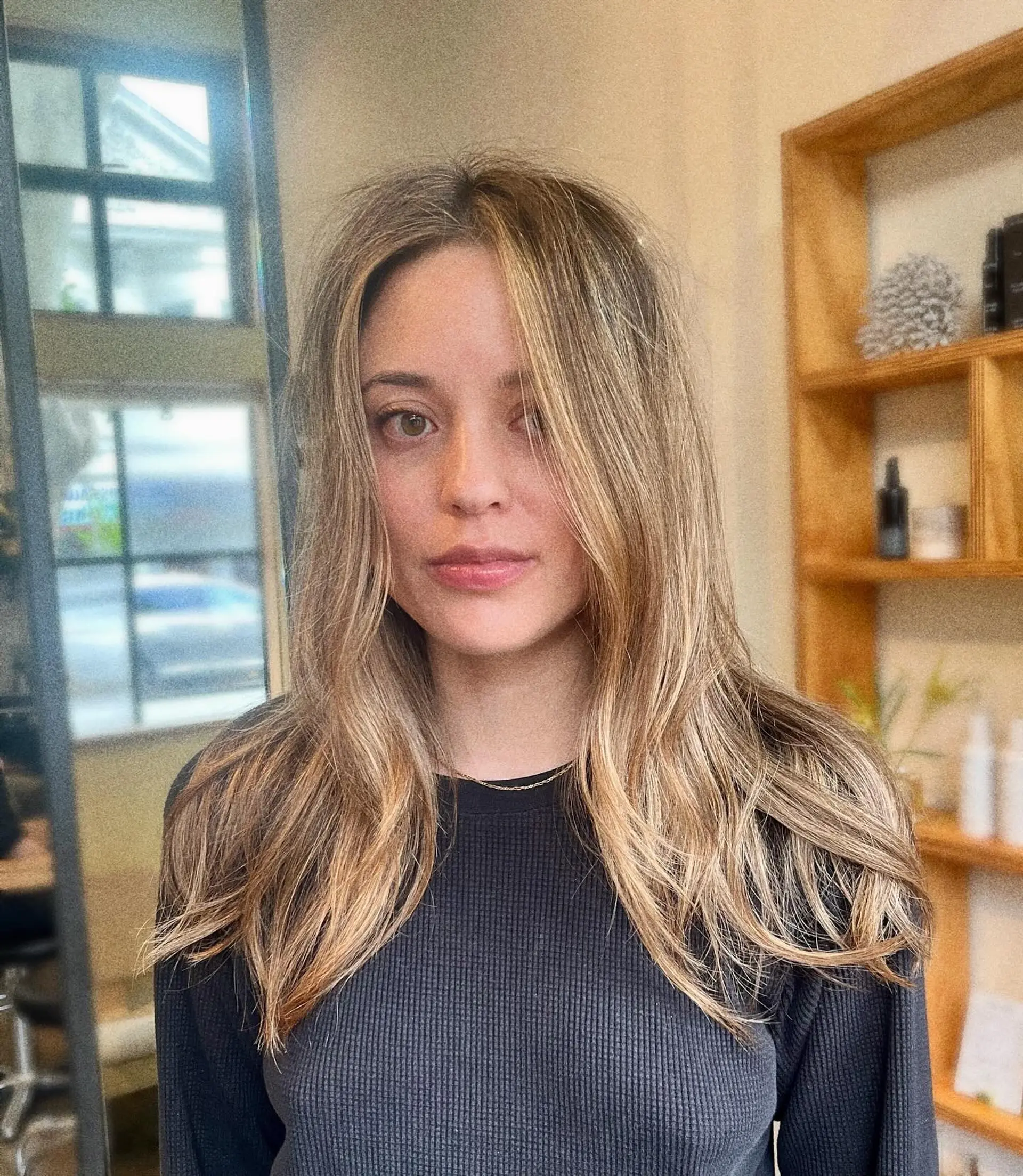 Long hair styled with soft waves featuring a sun-kissed blonde balayage and face-framing highlights. 1