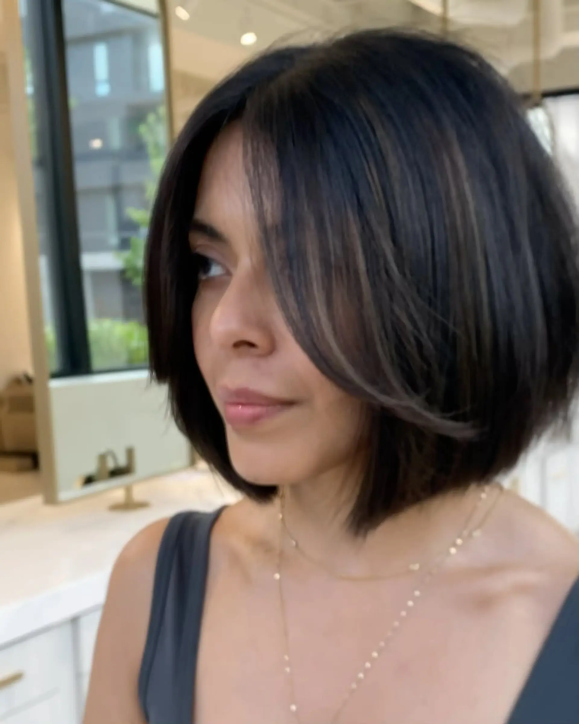 A sleek, chin-length dark brunette bob featuring subtle face-framing layers and soft curtain bangs. 1