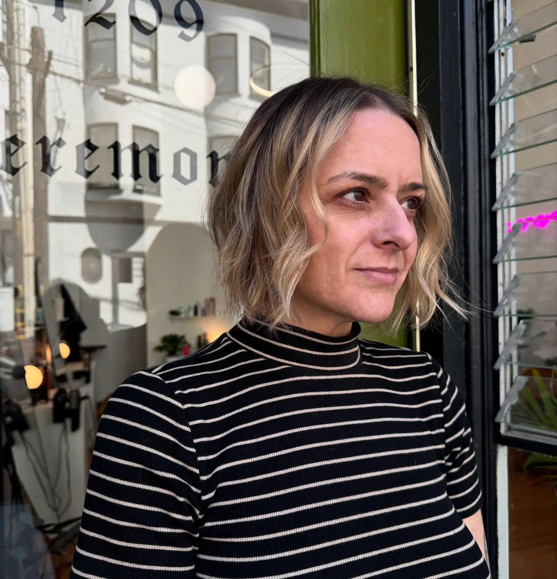 A chin-length textured bob styled with subtle loose waves and dimensional blonde highlights. 1