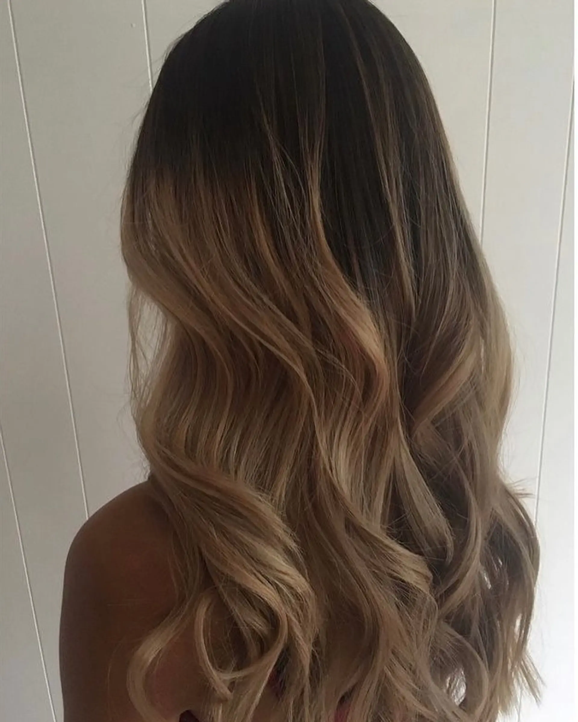 Long cascading waves featuring a seamless balayage transition from deep brown roots to warm caramel and honey blonde tones. 1