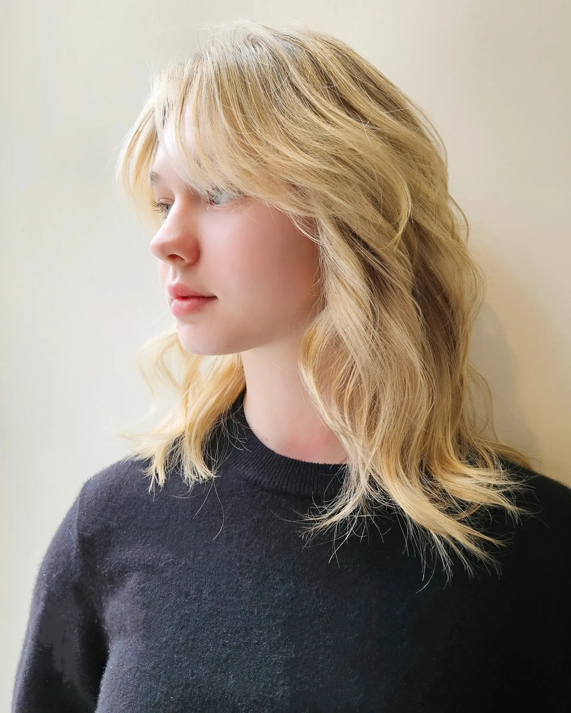 A medium-length warm blonde layered shag with feathered curtain bangs and soft, textured waves. 1