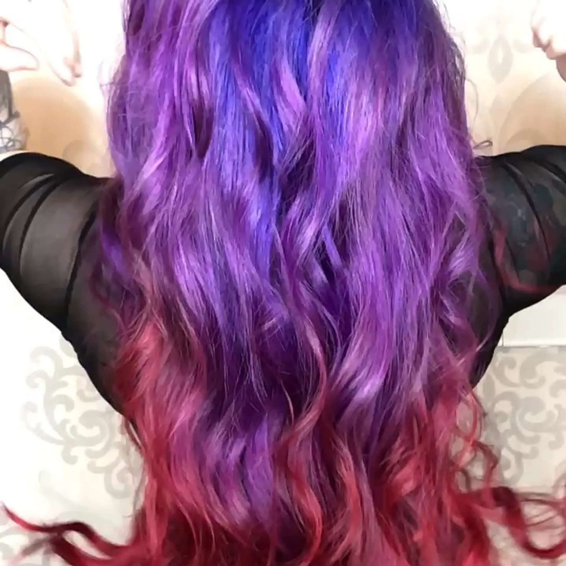 Long wavy hair featuring a seamless color melt transitioning from deep violet purple at the top to vibrant magenta and red at the ends. 1