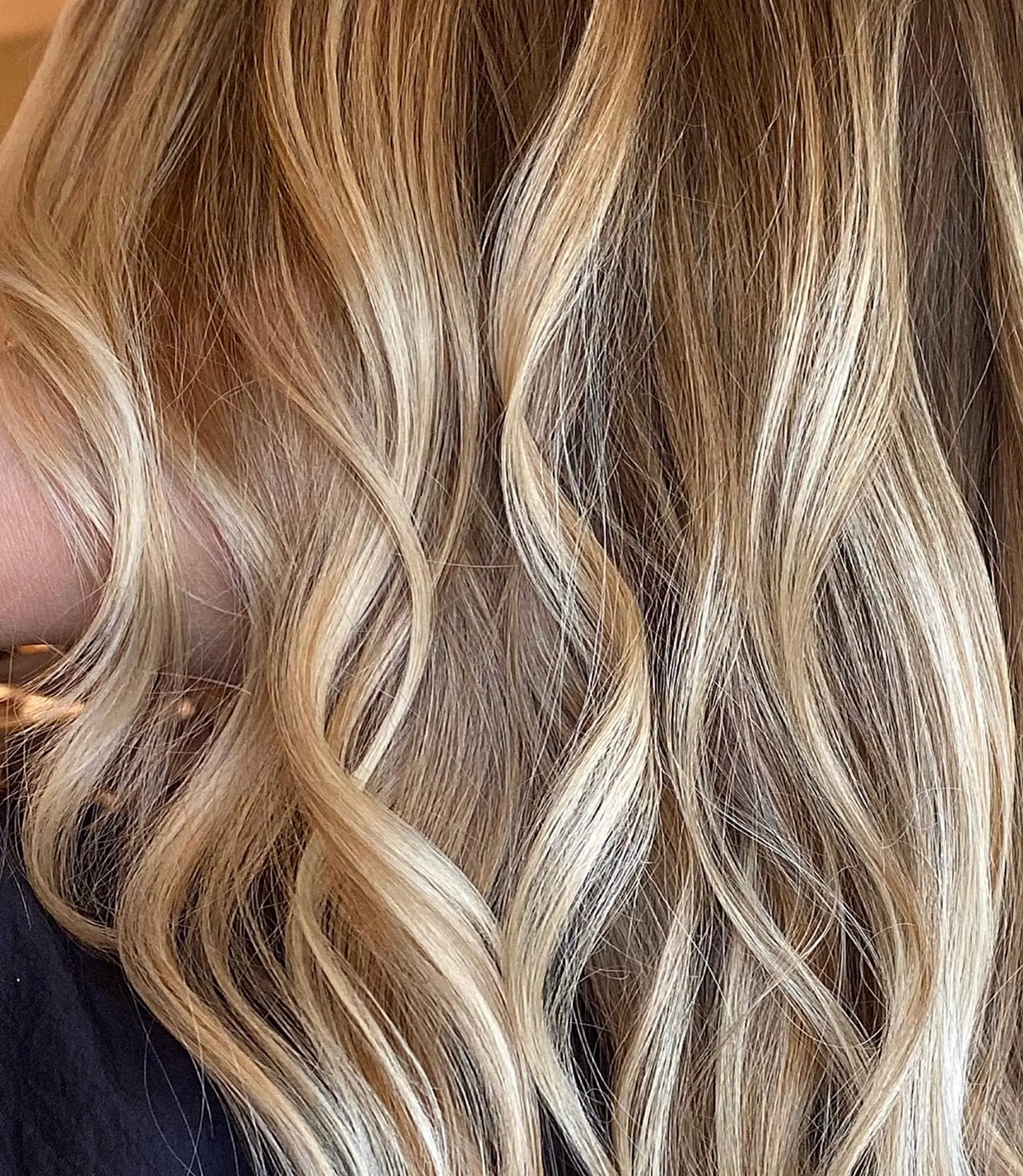 Close-up view of dimensional golden blonde hair styled into loose, flowing waves. 1