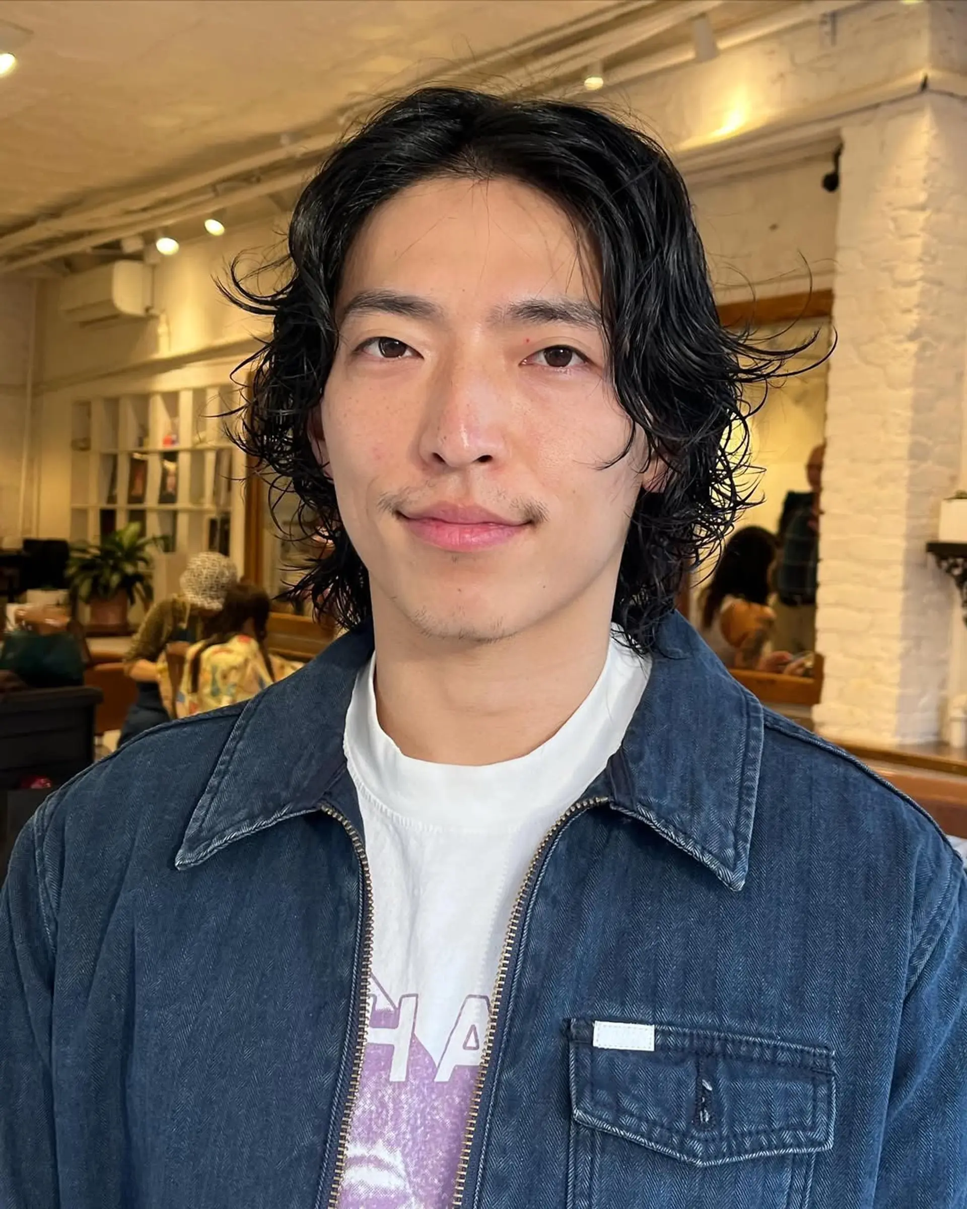 A medium-length, wavy cut + perm with black, layered locks, featuring a center part for a relaxed and stylish look. 1