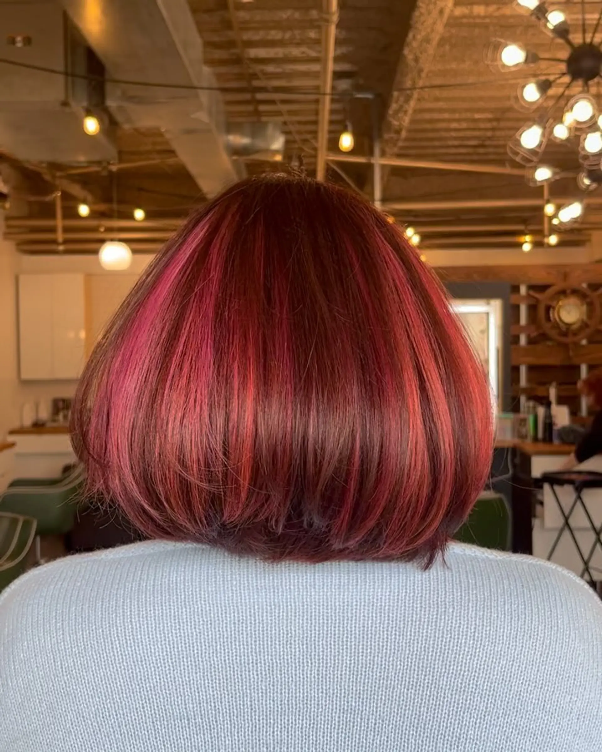 A sleek, chin-length rounded bob featuring deep red and auburn tones accented with bold magenta-pink streaks. 1