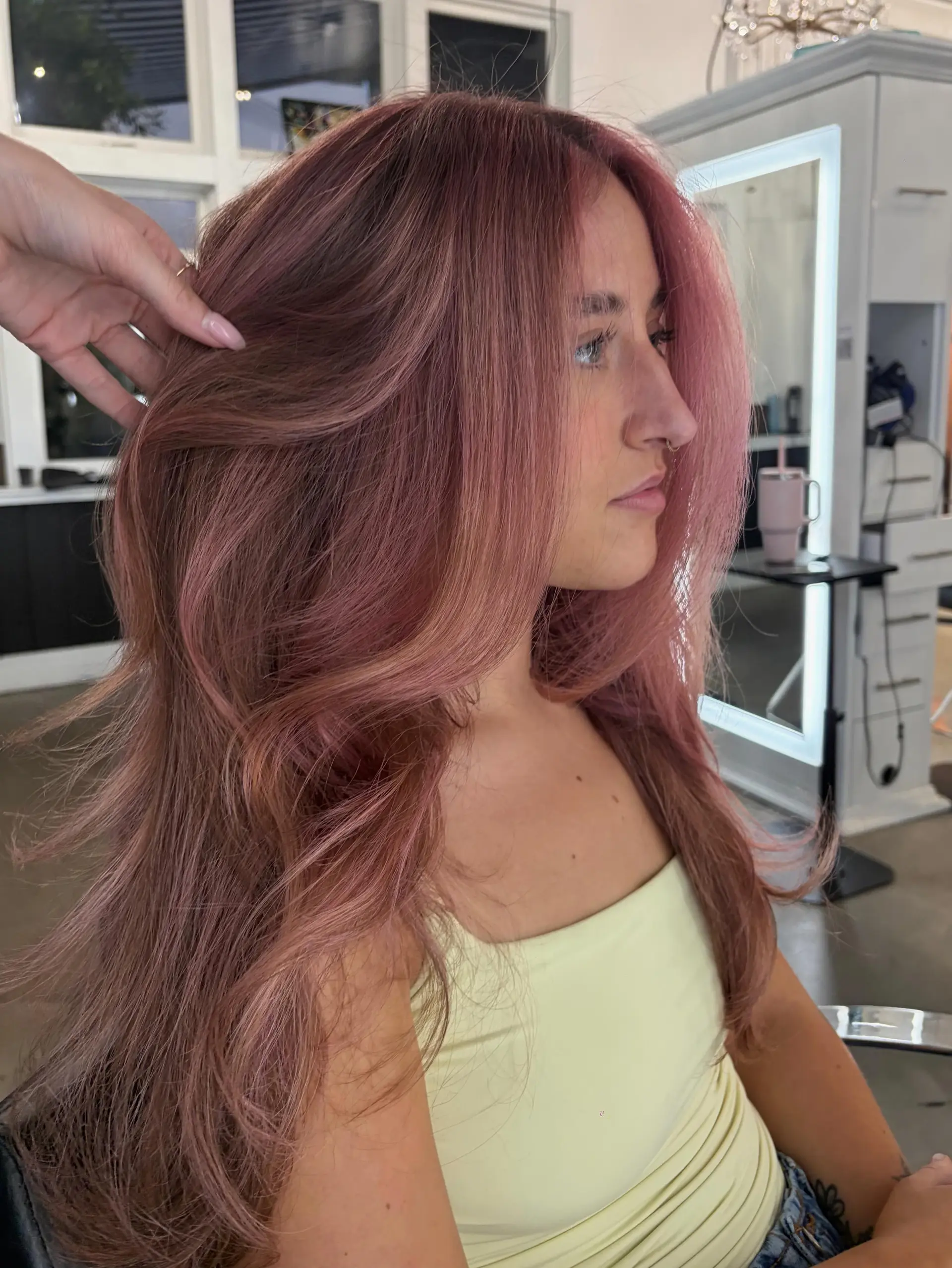 A voluminous blowout featuring long, face-framing layers colored in a muted dusty rose tone. 1