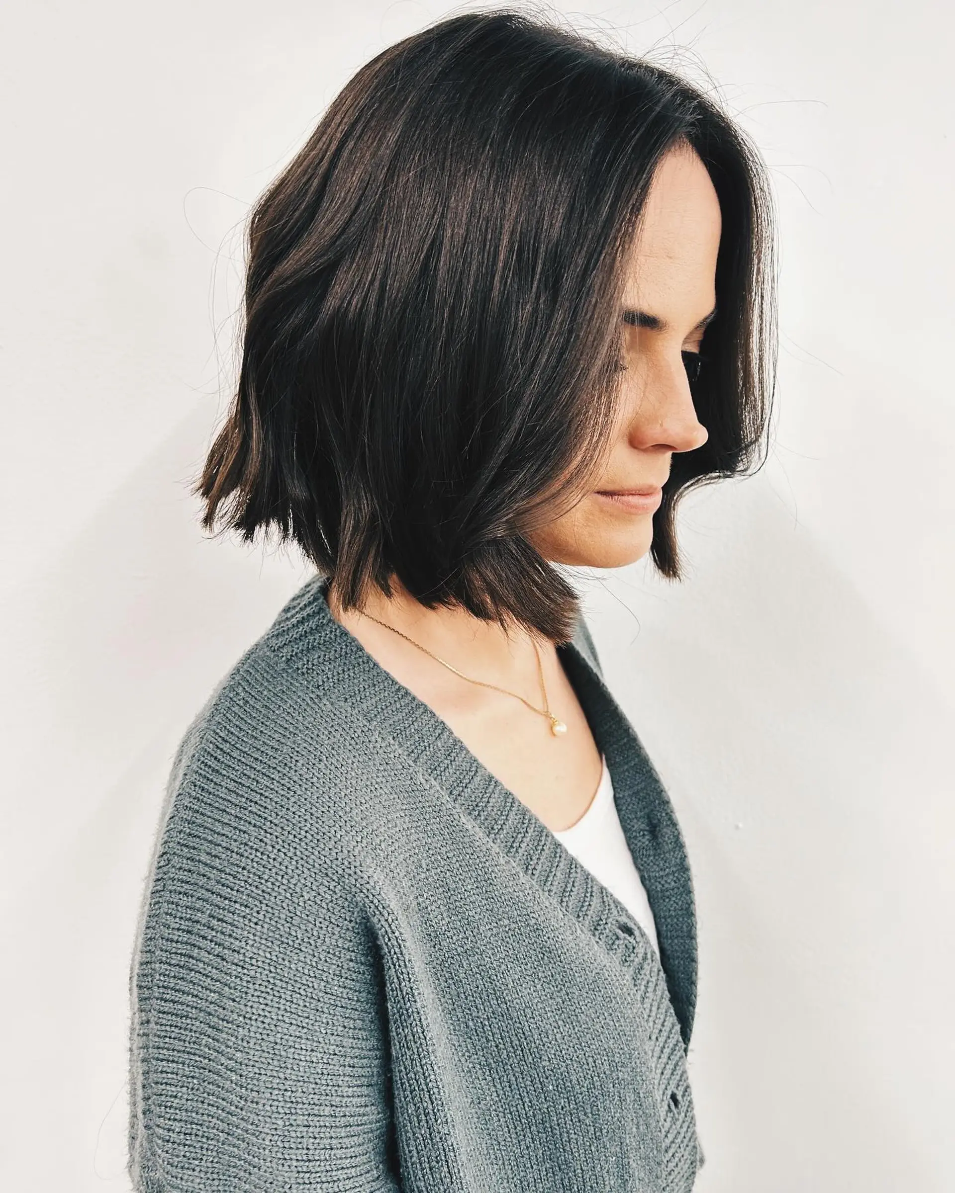 A blunt, textured chin-length bob in deep brunette styled with soft, undone waves. 1
