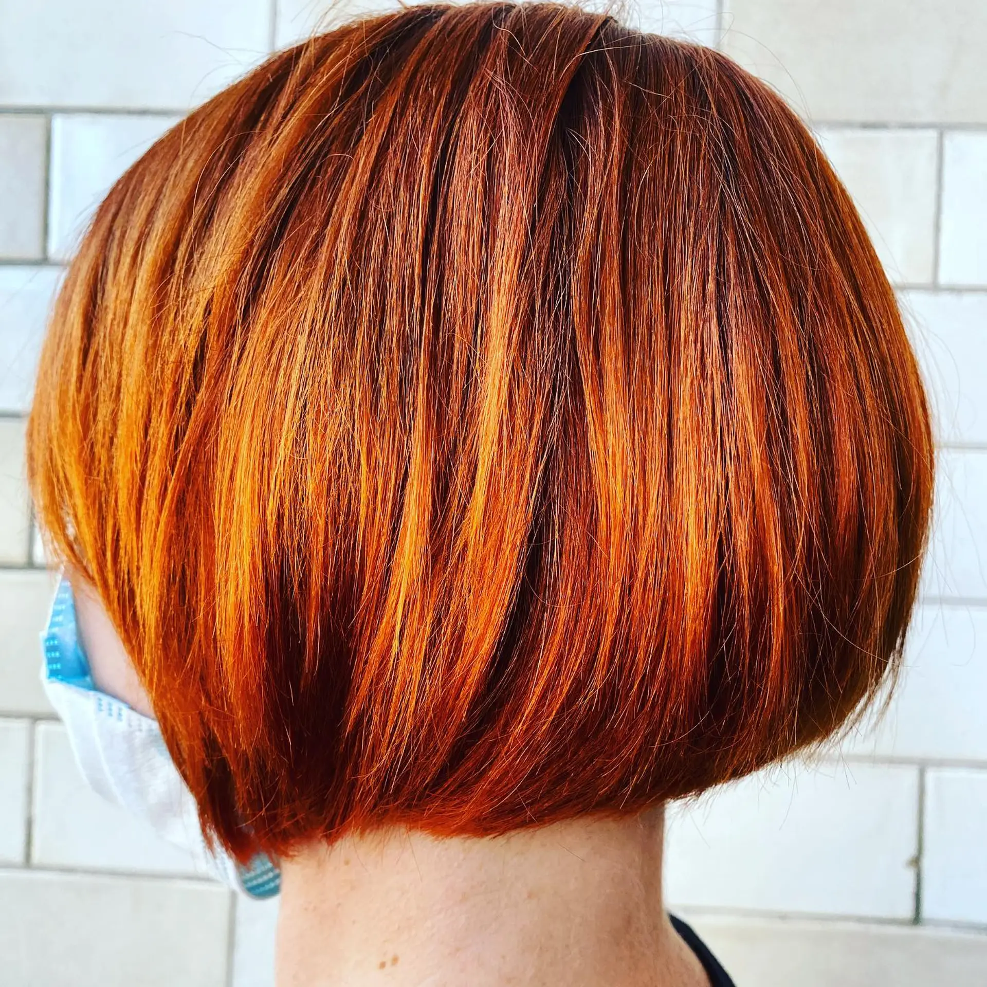 A sleek, rounded short bob cut styled straight in a vibrant warm copper red tone. 1