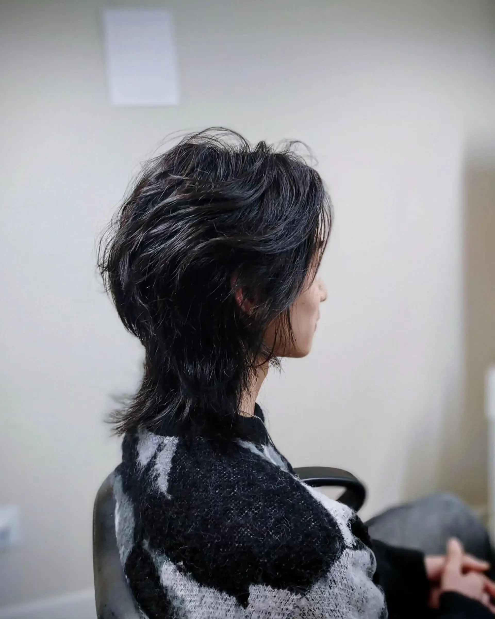 A medium-short textured wolf cut featuring feathered layers and tapered length extending at the nape. 1