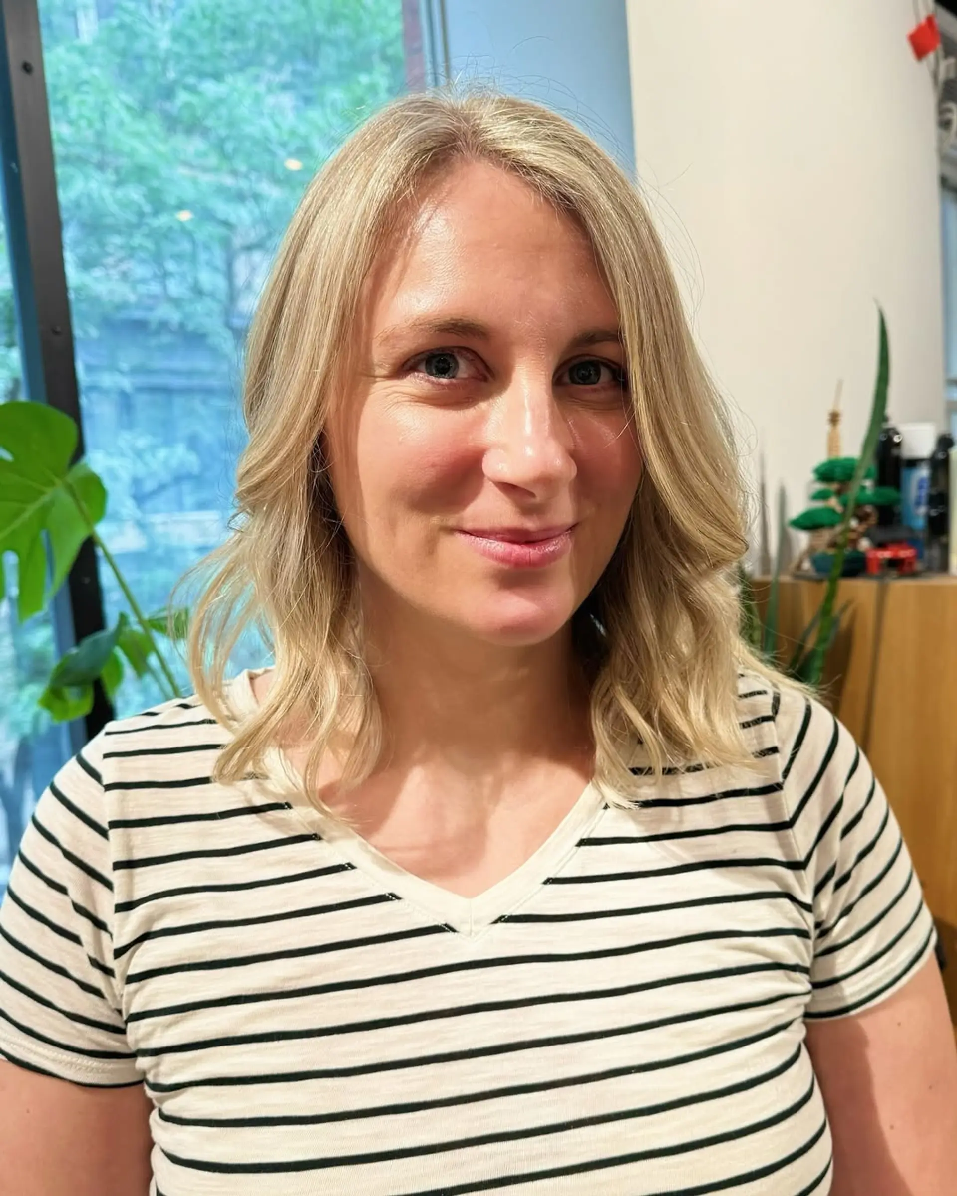 This hairstyle features medium length blonde hair styled in soft, beachy waves with subtle layers. 1