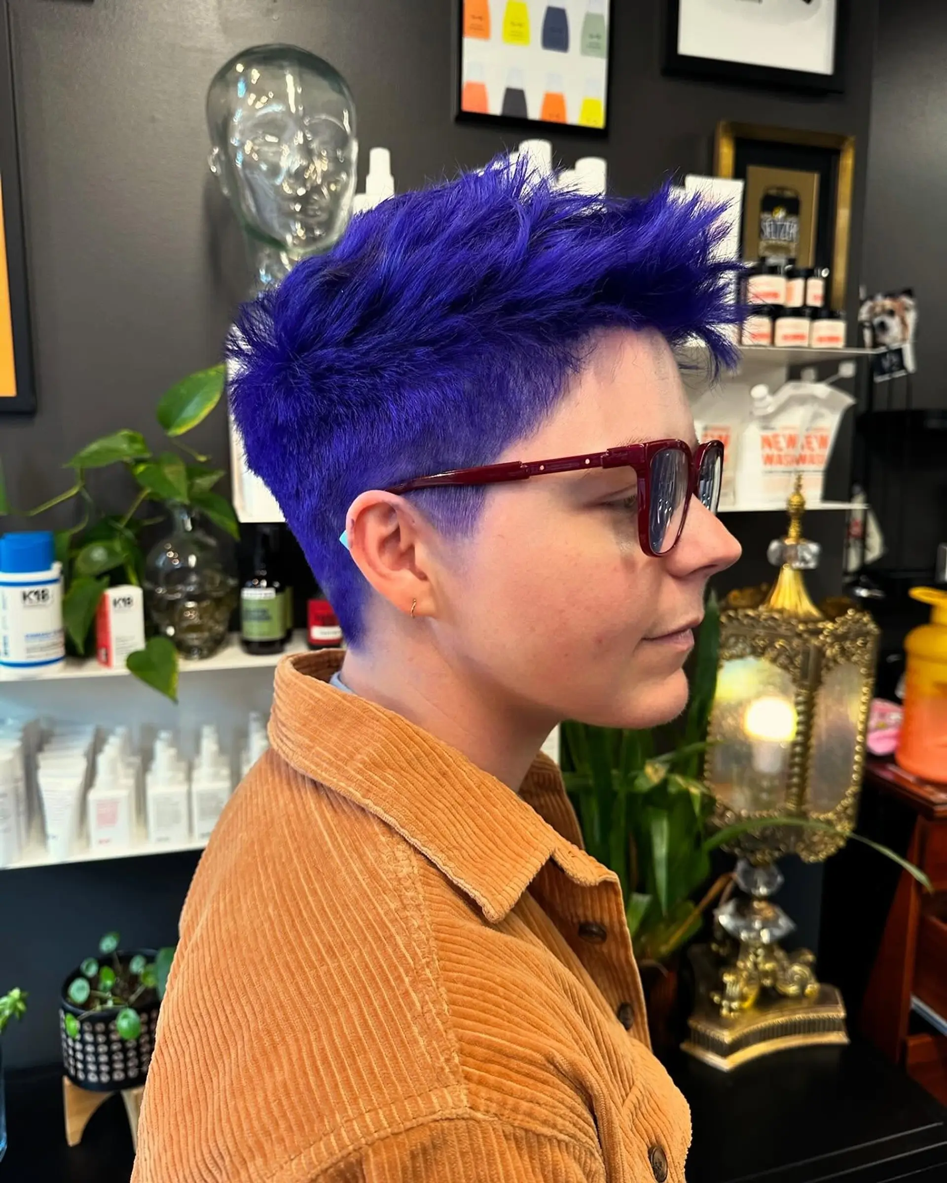 A textured pixie cut with closely clipped sides and voluminous, piecey length on top, dyed an electric blue-violet hue. 1