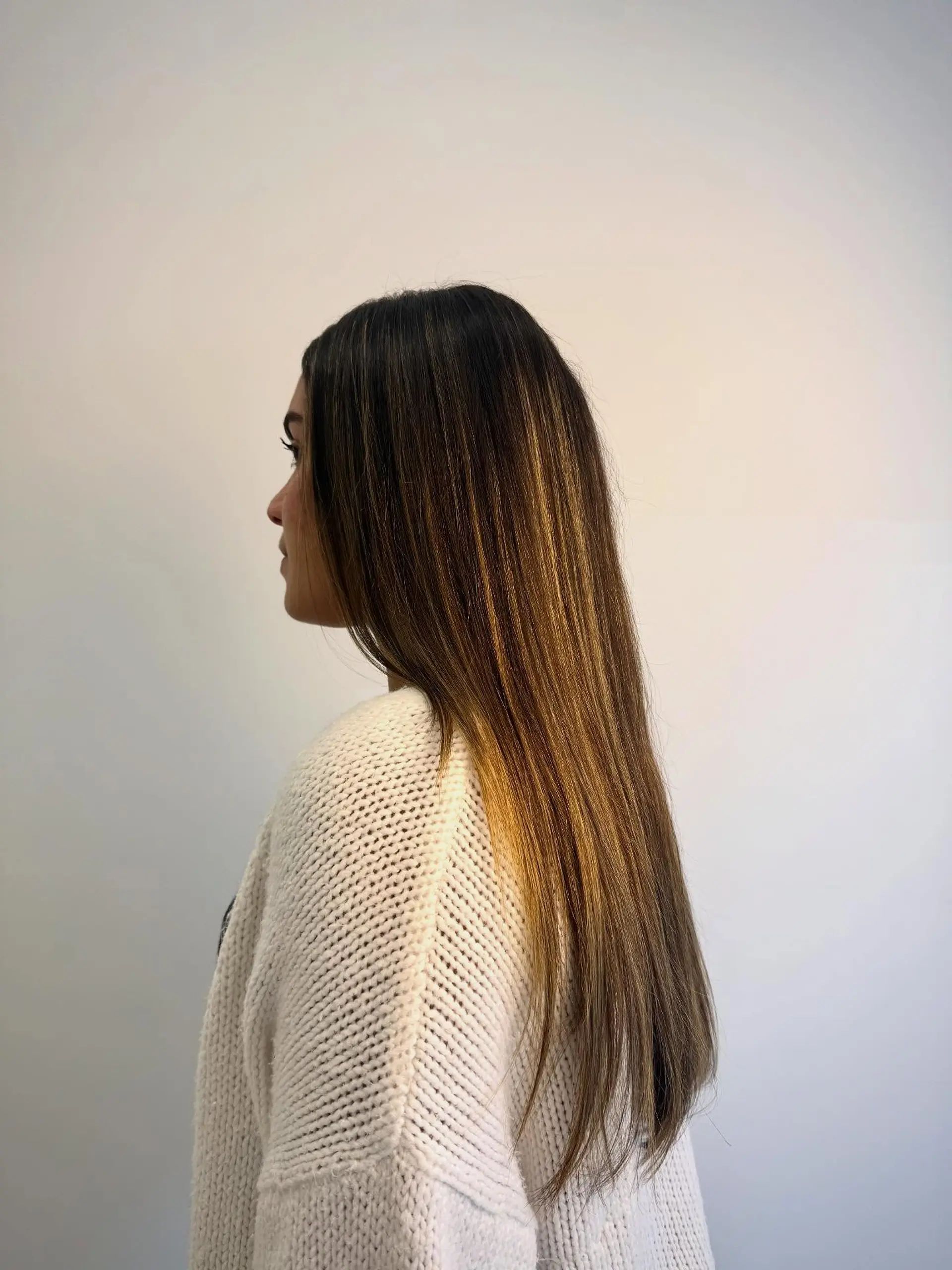 Long, sleek straight hair with warm caramel highlights styled into a smooth blowout. 1