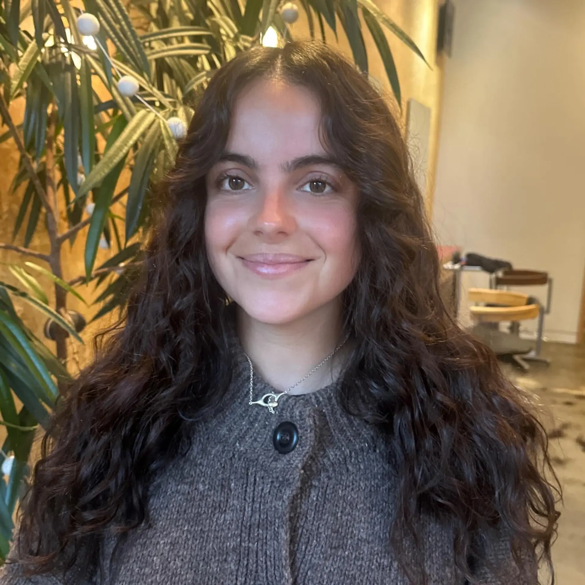 Long dark curly hair cut with a center part and soft face-framing layers. 1