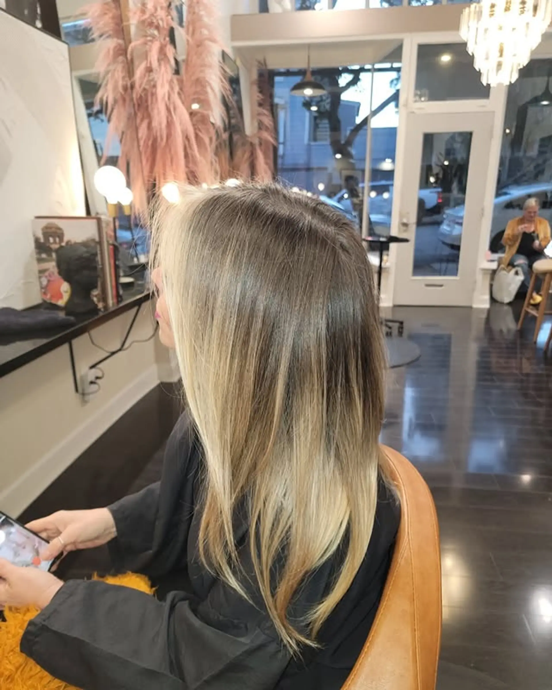 This style features long, straight hair with subtle layers for movement and body. The color is a natural-looking balayage, transitioning from a darker blonde/light brown root to lighter ash blonde ends. 1