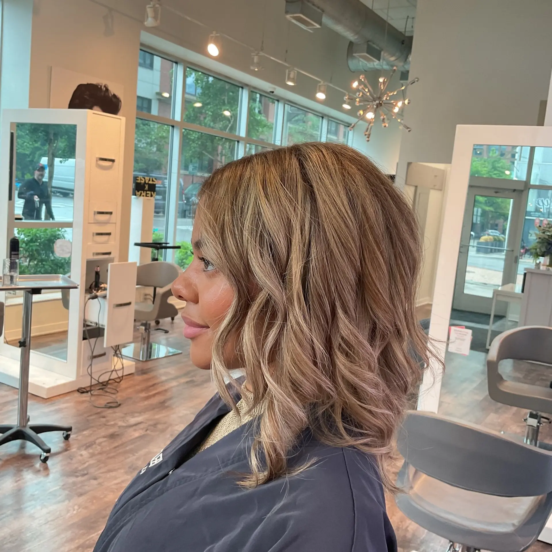 A medium-length wavy hairstyle with a dimensional ash blonde color created through balayage techniques. 2