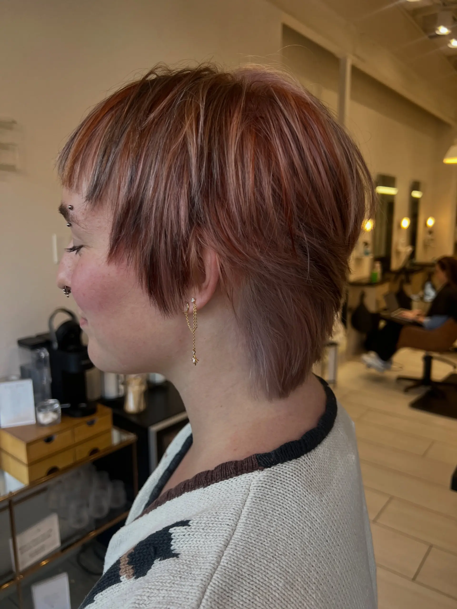 A textured short pixie mullet cut showcasing multi-toned calico color with warm copper, soft mauve pink, and subtle brunette dimension. 1