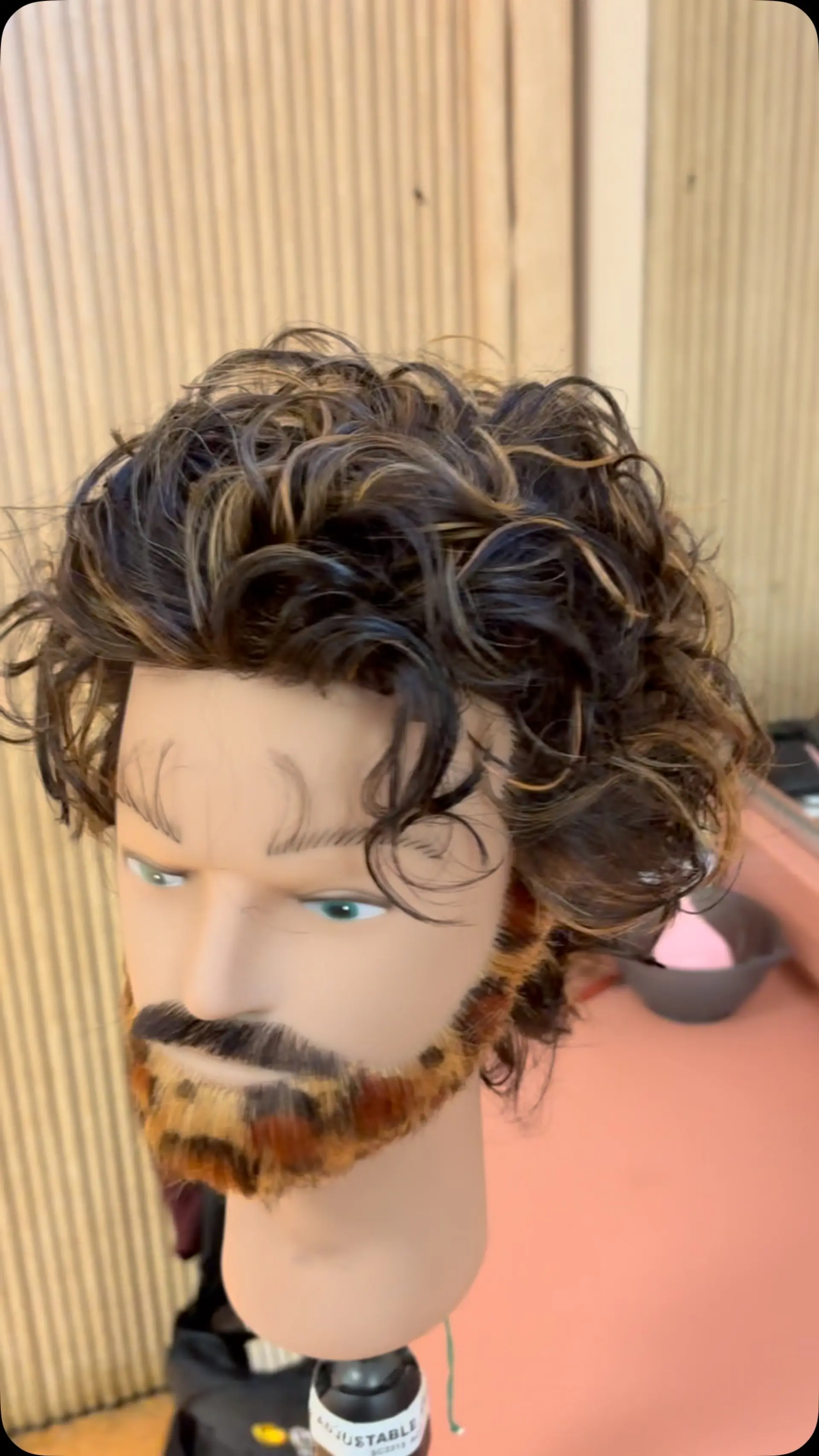 Layered, tousled curls with subtle caramel highlights displayed on a mannequin head. 1